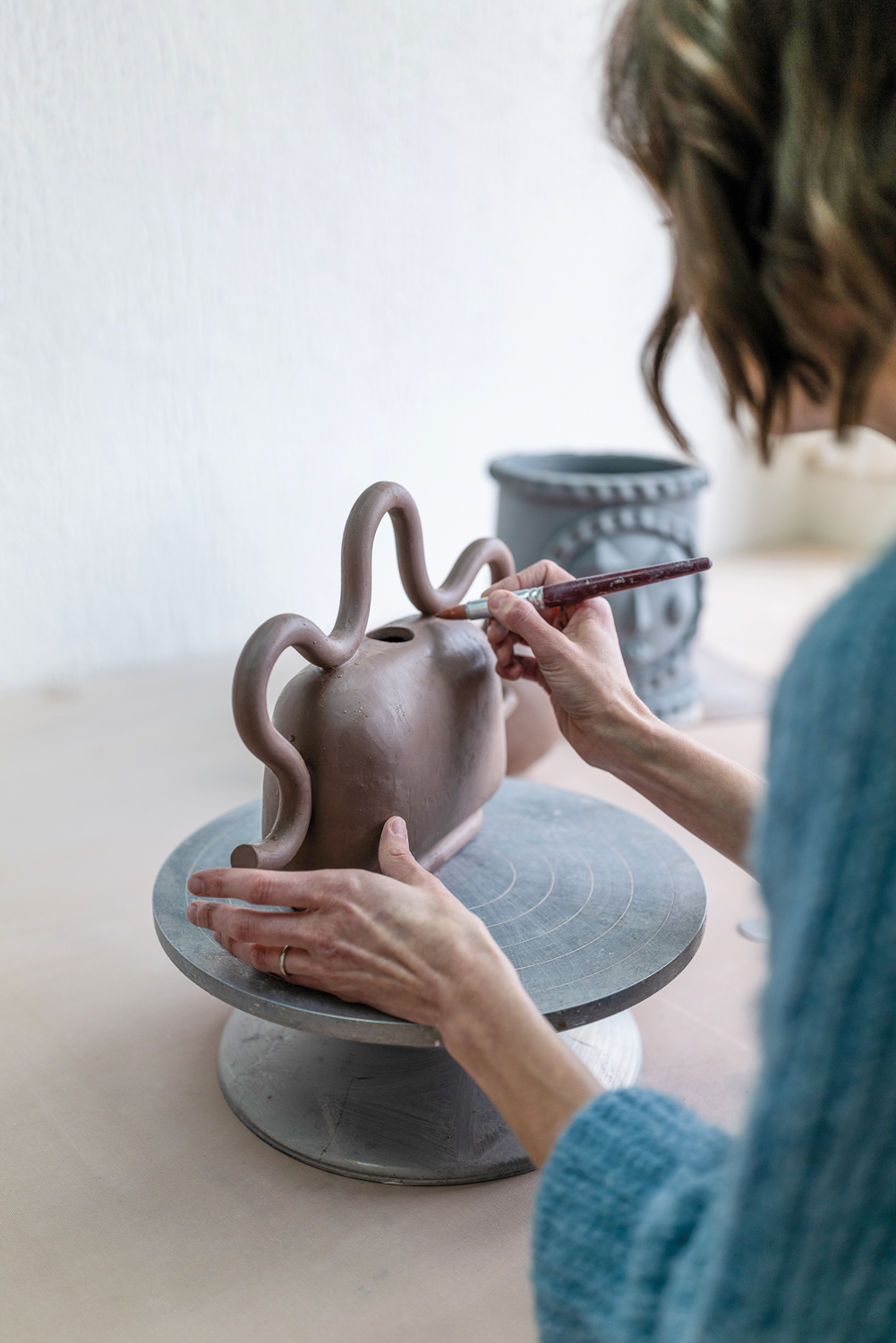 Woman hand-brushing a piece of unfired pottery