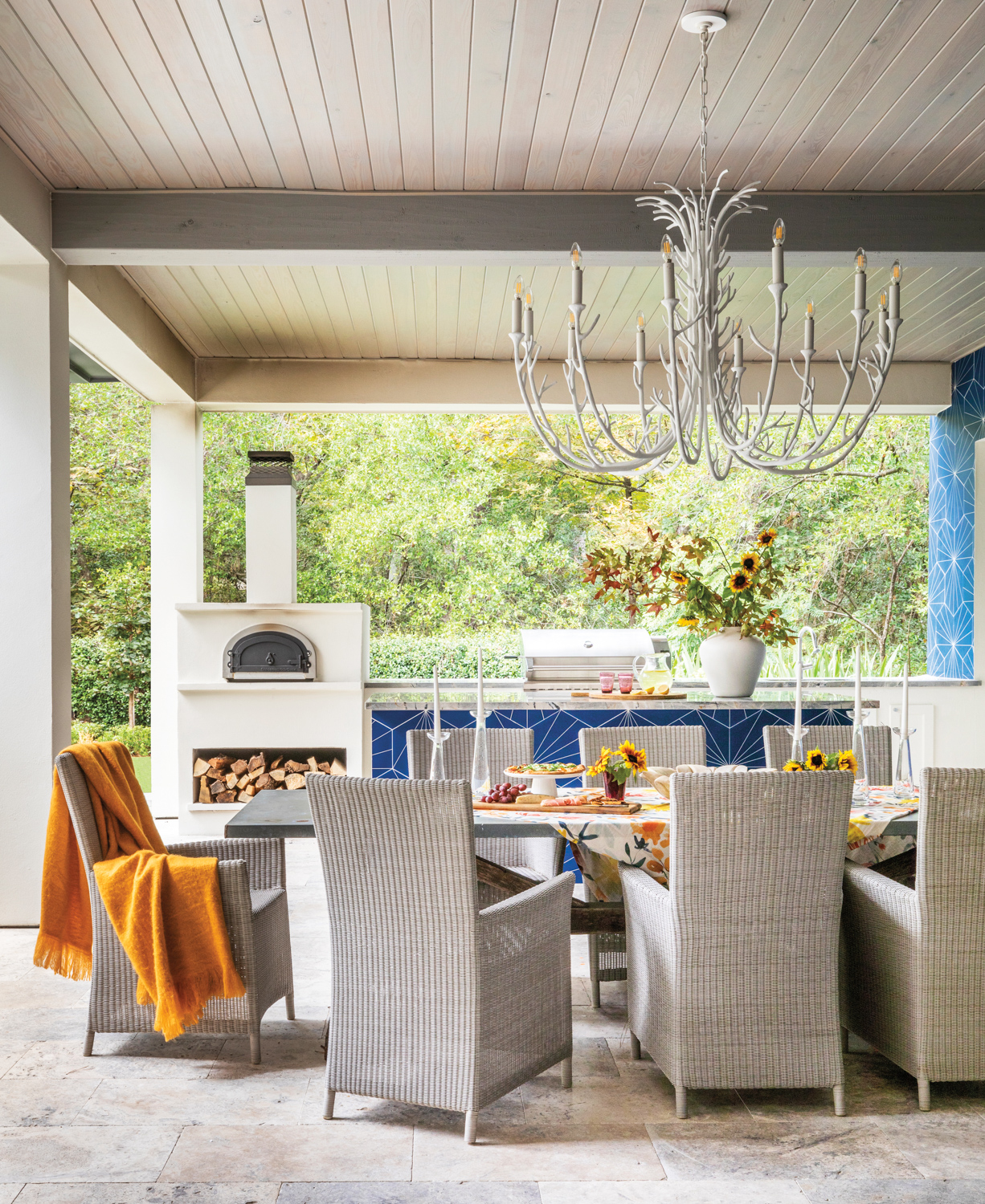 outdoor dining area with statement lighting, graphic blue tile and a pizza oven
