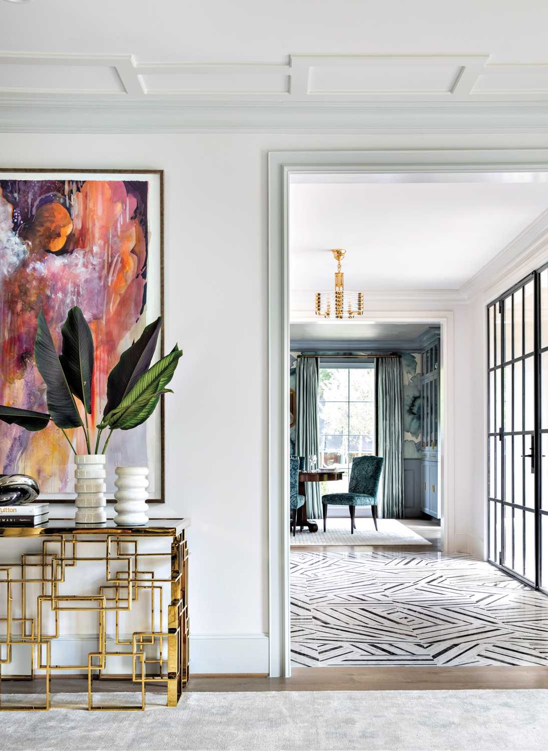 living room vignette featuring abstract art and a gold console with view of entry featuring marble flooring