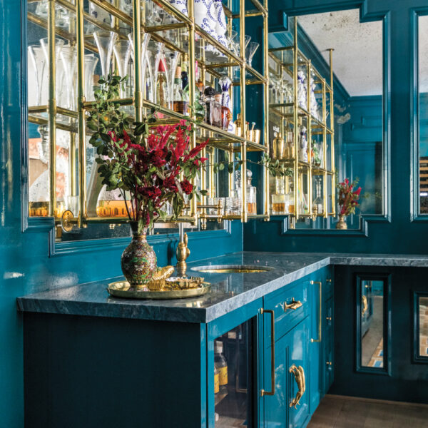 Take A Spin Around The Color Wheel In This Vibrant Houston Gem Bar area with turquoise cabinetry and brass and glass open shelving