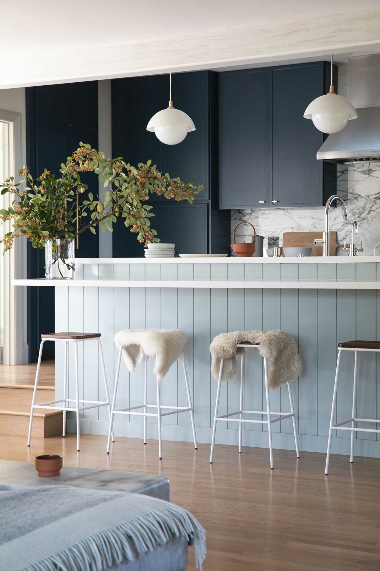 kitchen with dark blue cabinetry, light blue island and white counter stools