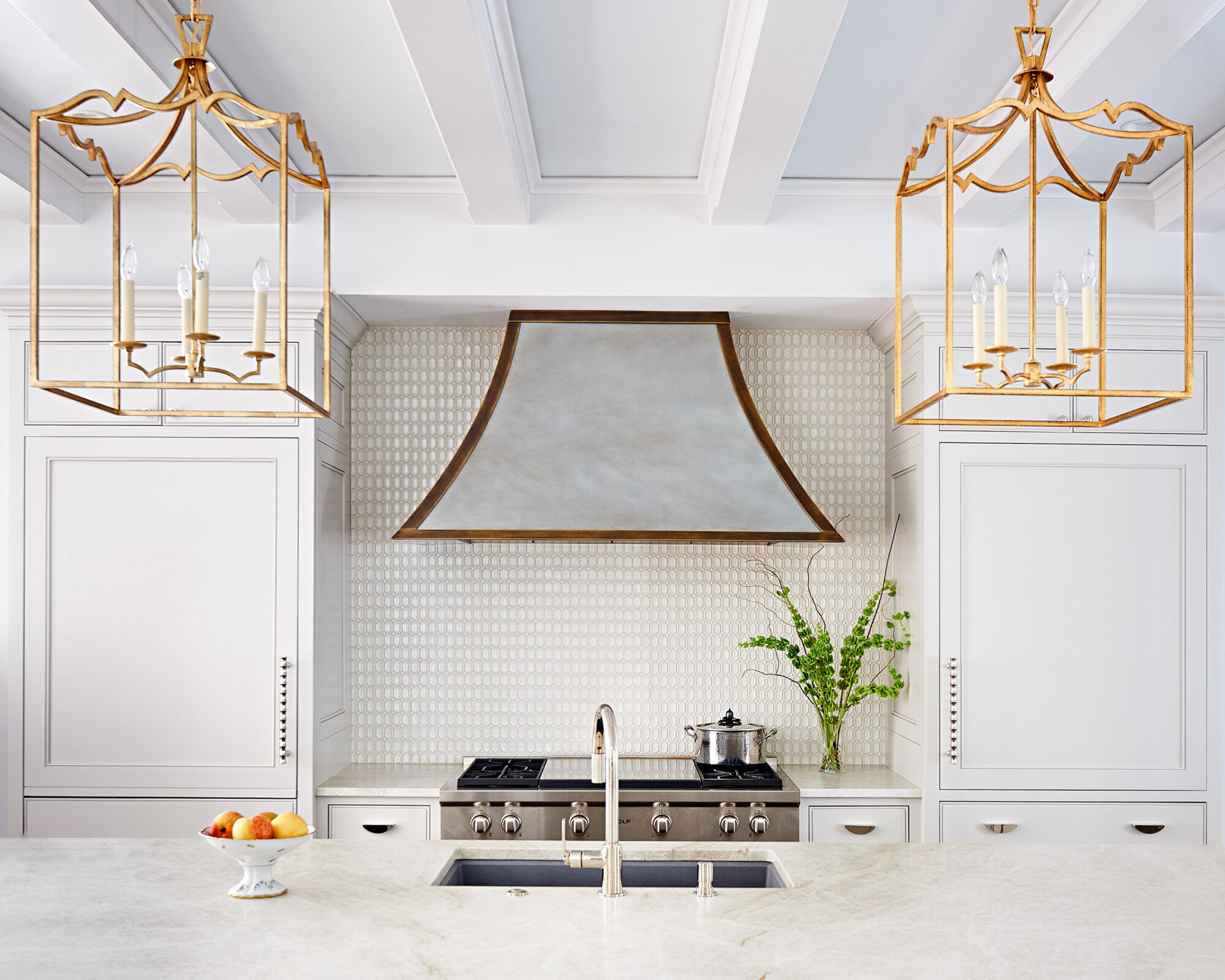 kitchen with white cabinetry, oversize gold lanterns and large silver range hood