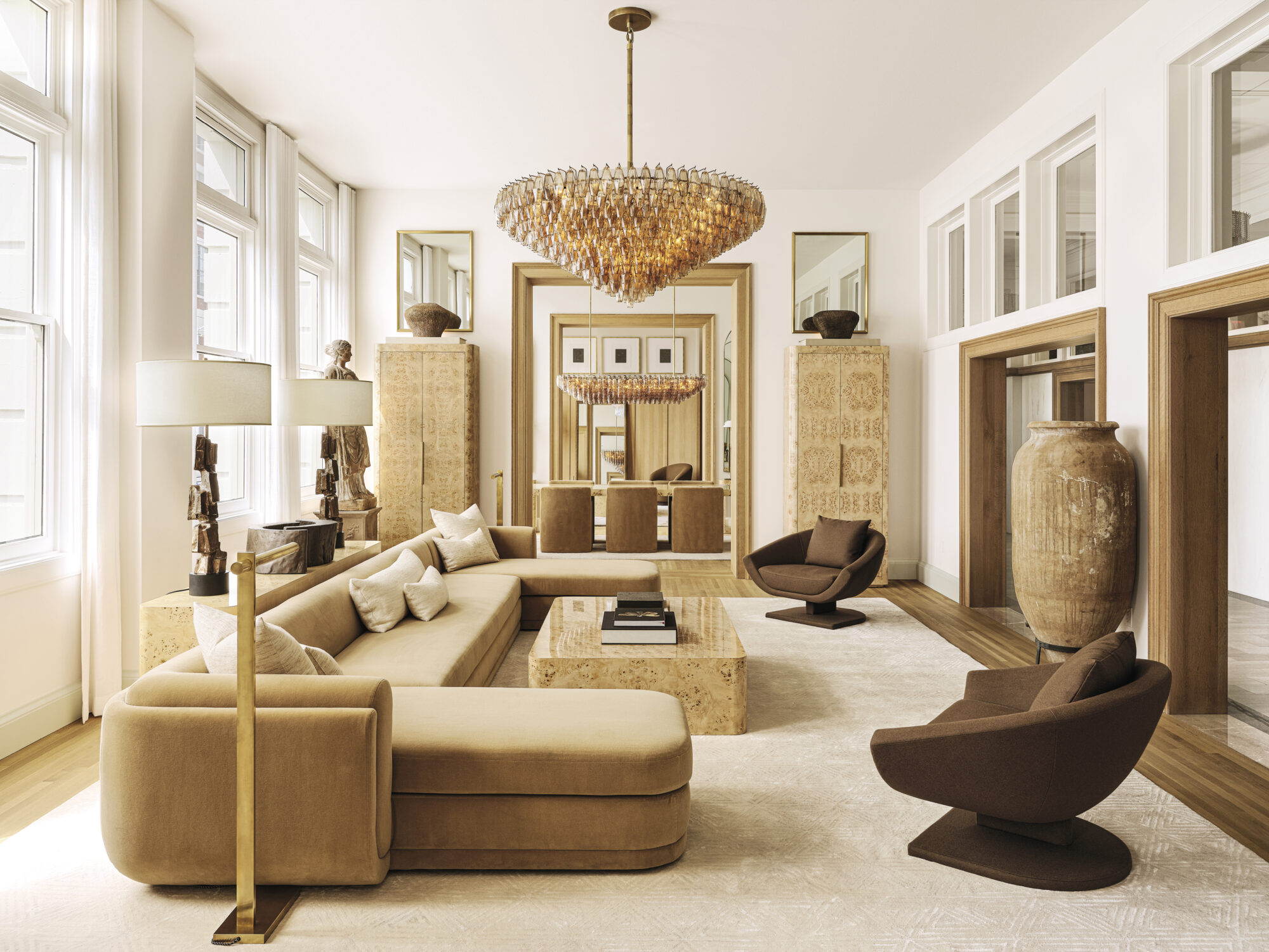 RH showroom space with neutral furnishings, including a taupe sectional and brown armchairs.