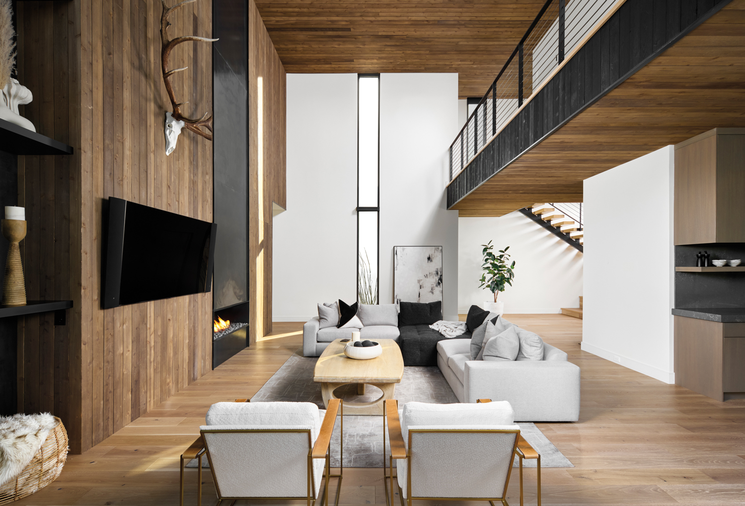 A double-story living room with wood panel walls and gray seating.