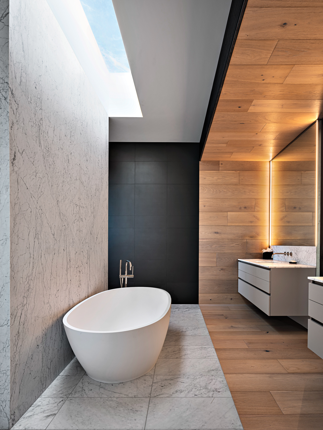 A bathroom with a pair of floating vanities and a curvaceous stand-alone tub