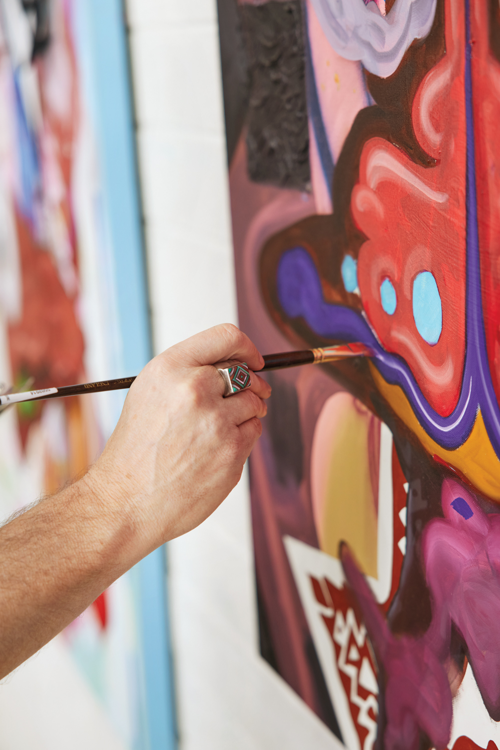 An artist's hand painting a colorful work.
