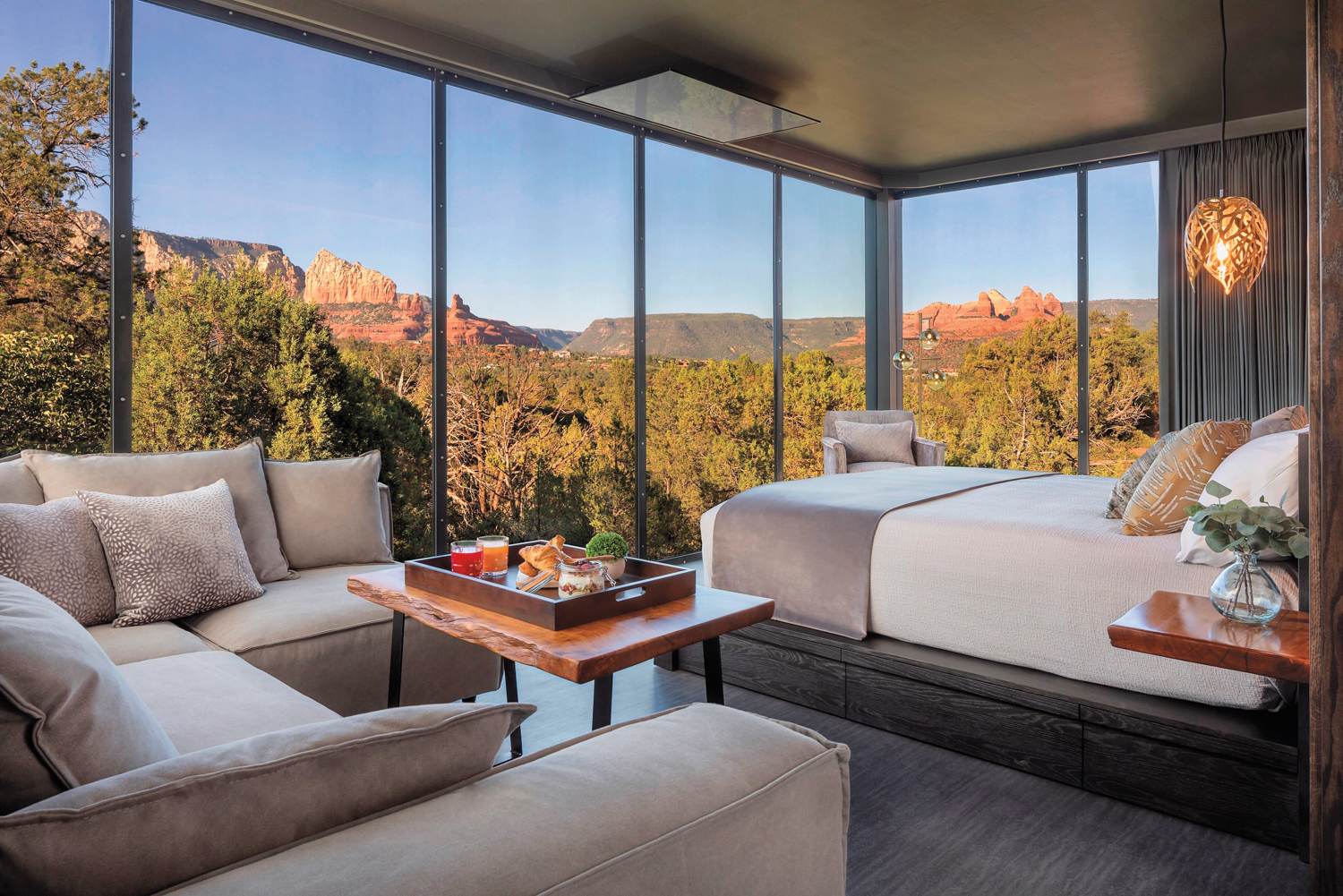 Ambiente Hotel room with floor-to-ceiling windows overlooking trees and red rock mountains