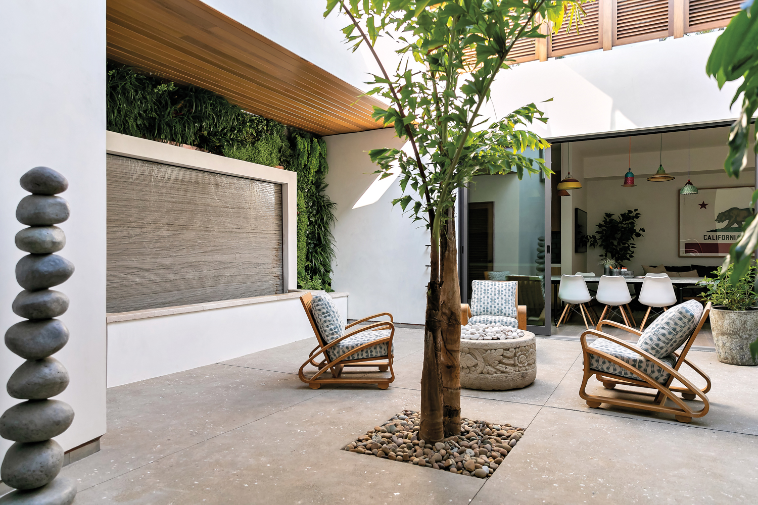 courtyard with lounge chairs, fire pit, fishtail palm tree and living wall