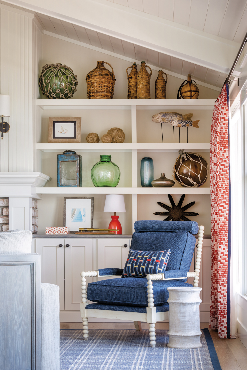 A blue armchair sits in front of white built-in shelves displaying a collection of objects.