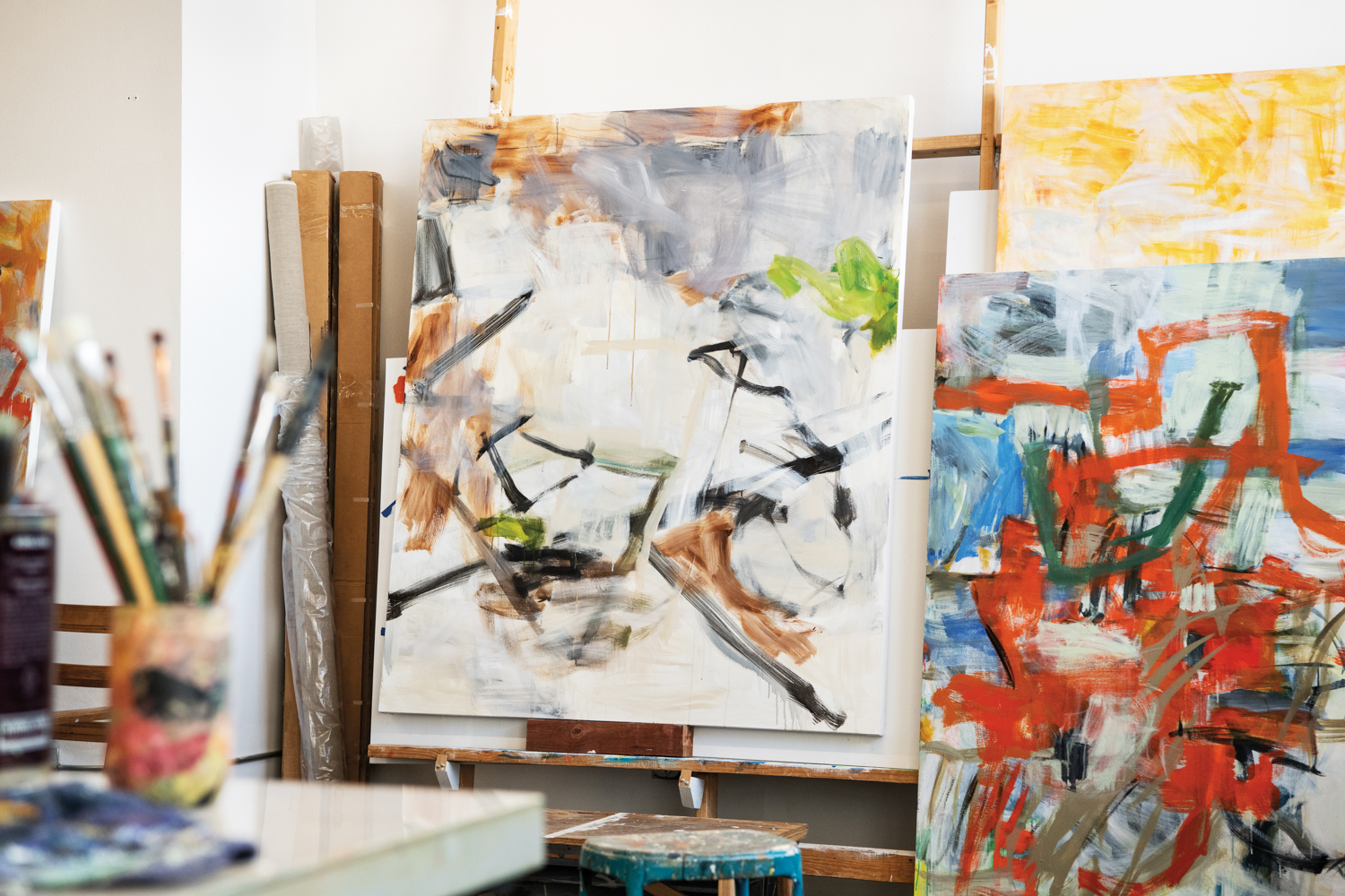 colorful abstract paintings stacked together in an artists studio