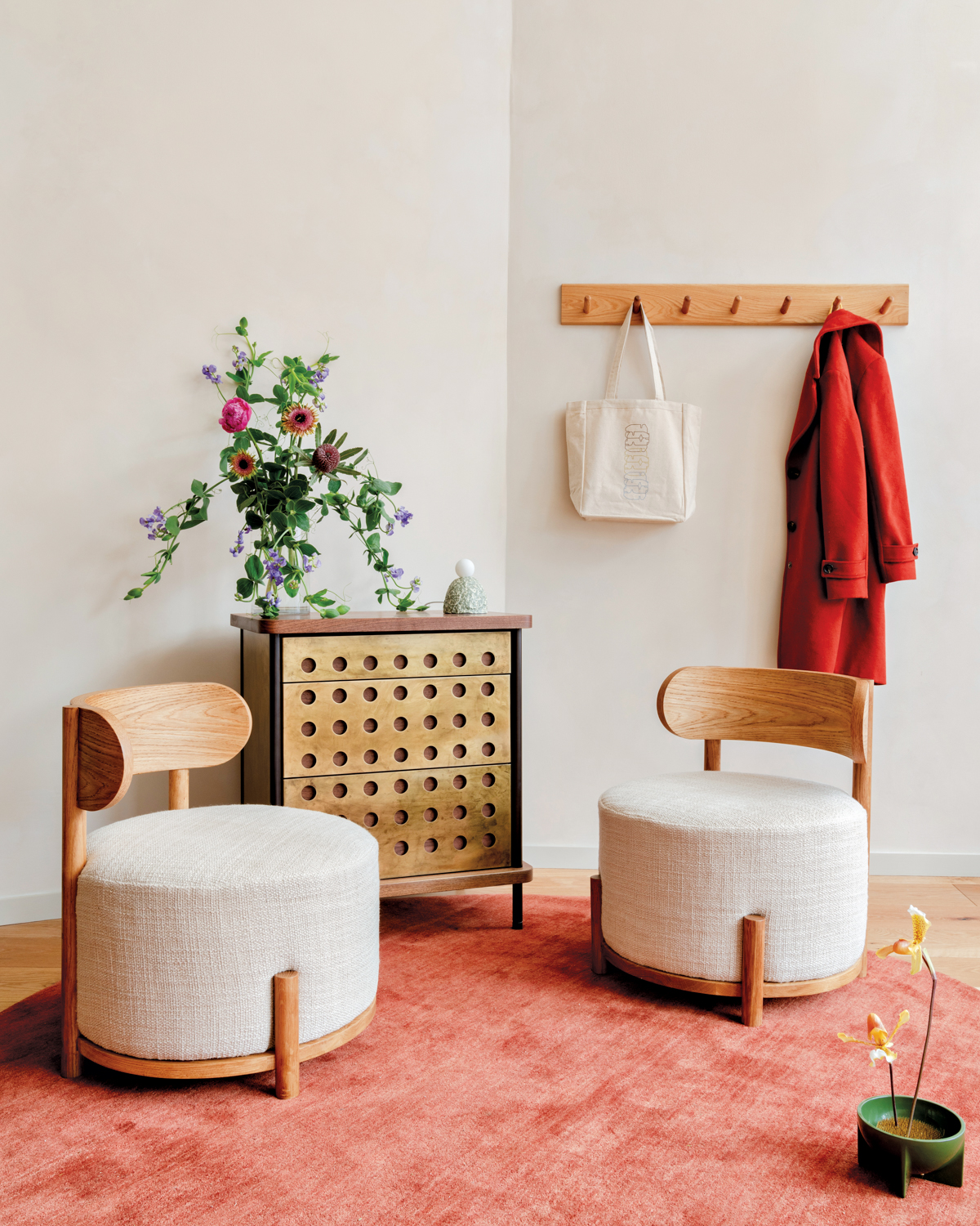 pink rug, two round chairs, a wood-and-metal side table and a coat hanger at Assembly Line