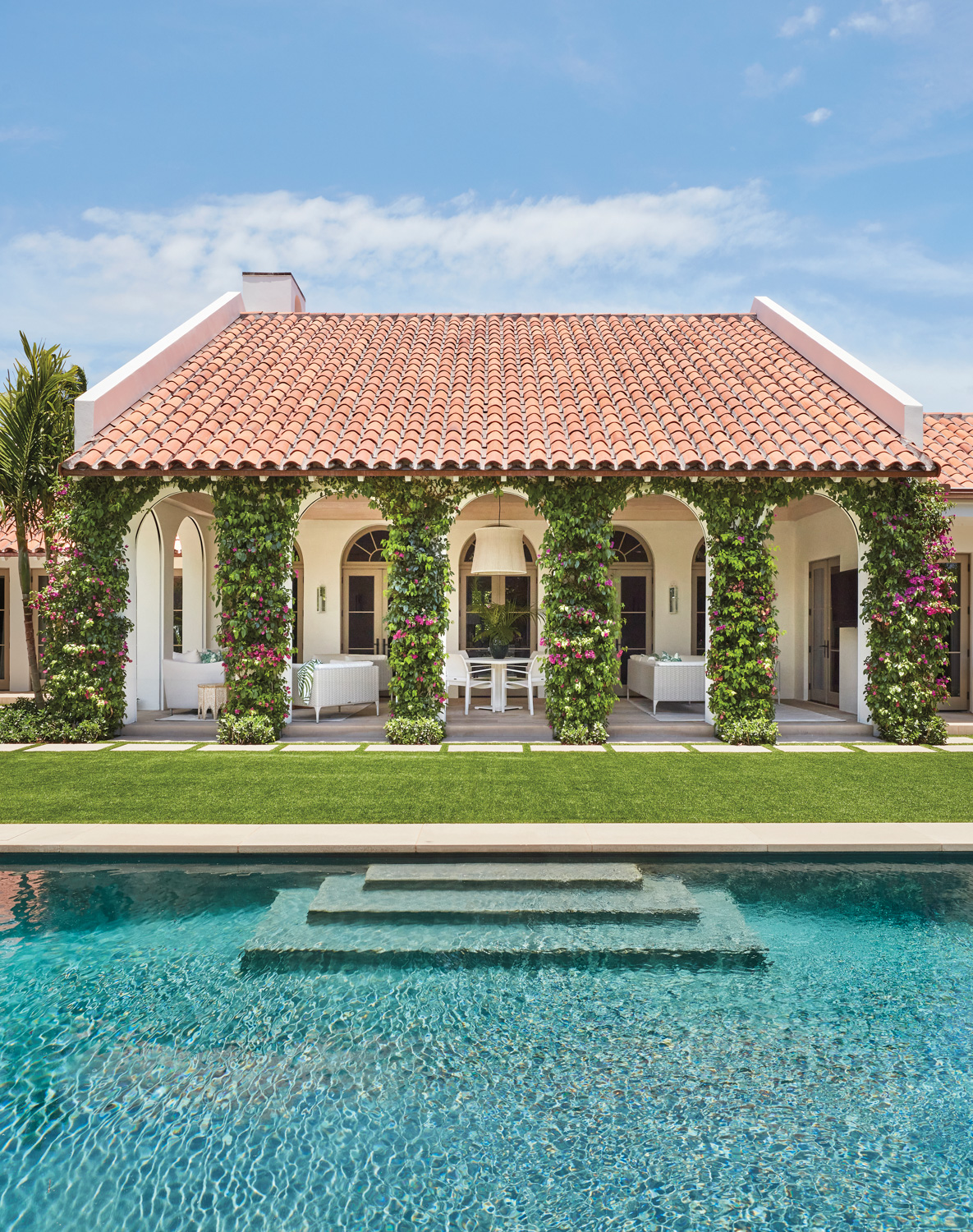 mediterannean-style loggia with bougainvillea on columns in front of pool