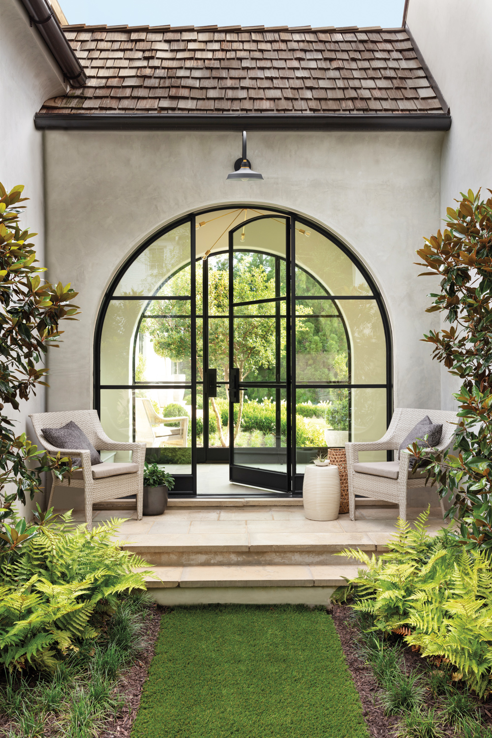Stucco-coated entryway with arched French doors and lush gardens