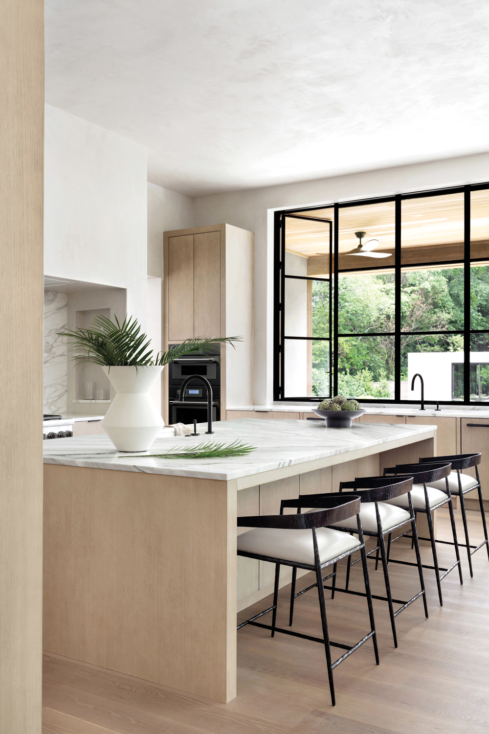 Minimalist kitchen with white oak cabinetry, plaster-coated vent wood and hinged steel windows