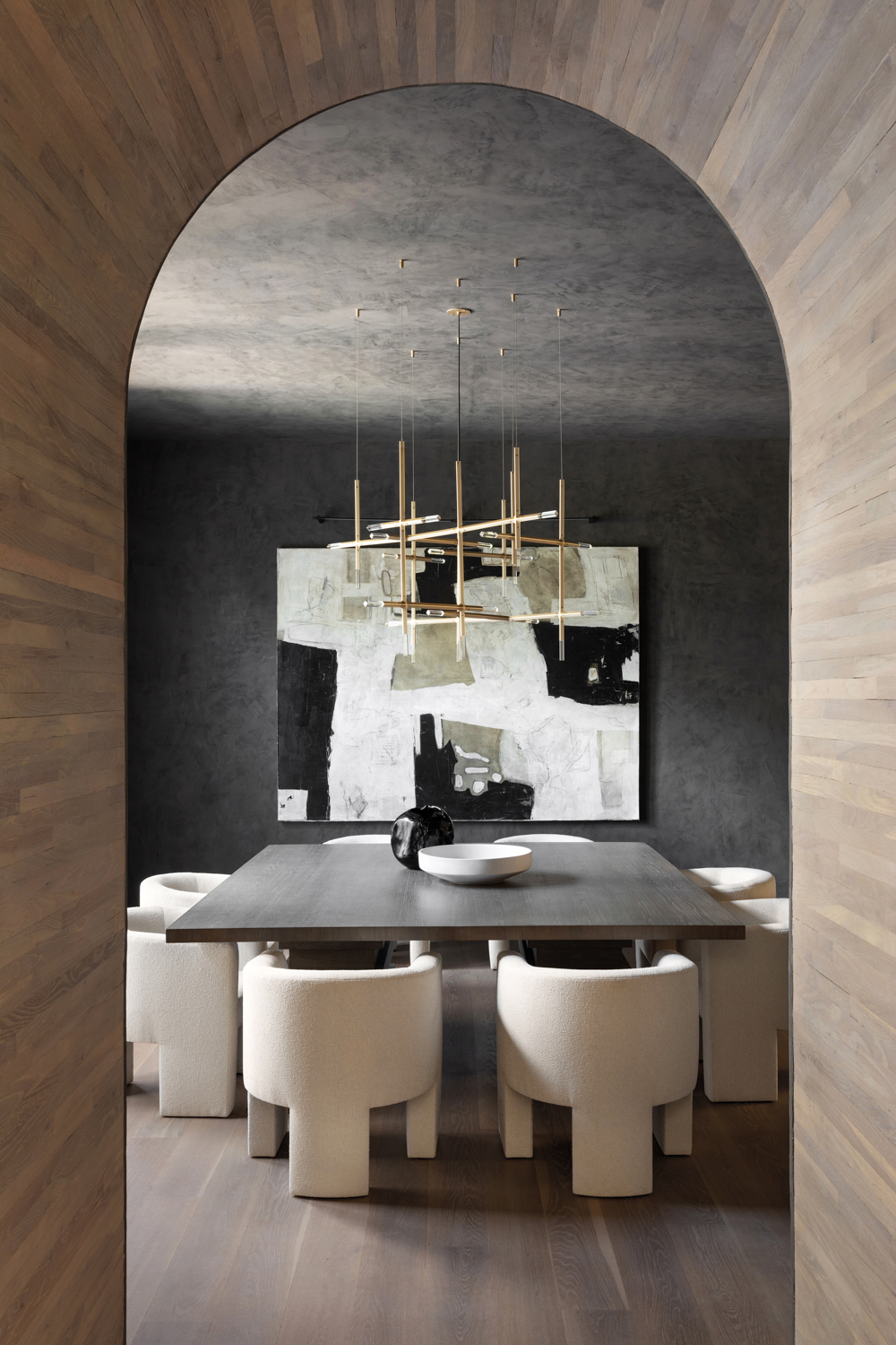 Dark dining room with curved doorway, black plaster walls, tripod chairs and abstract art