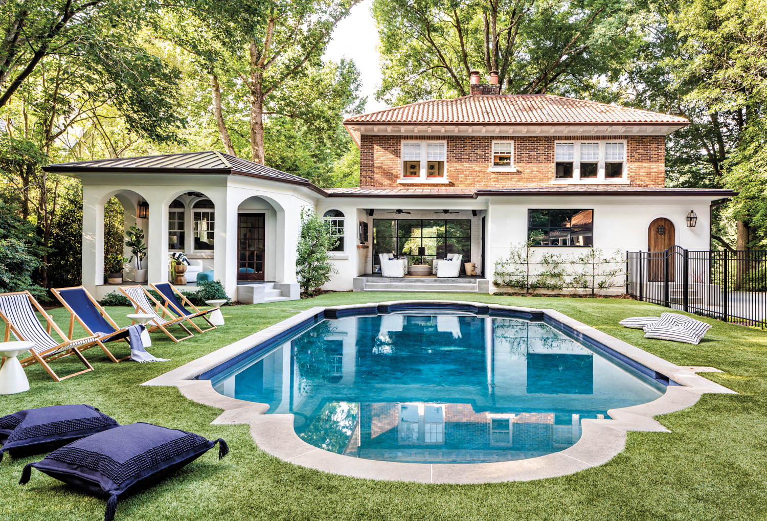 Backyard with large swimming pool, green grass and lounge furniture