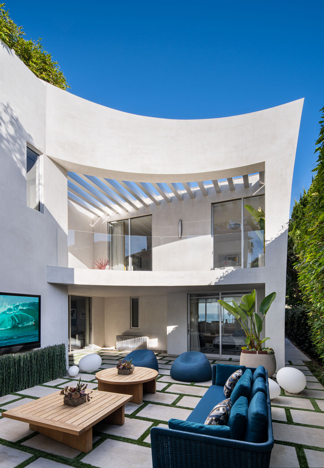 Modern white stucco house with outdoor lounge area and wall-mounted TV