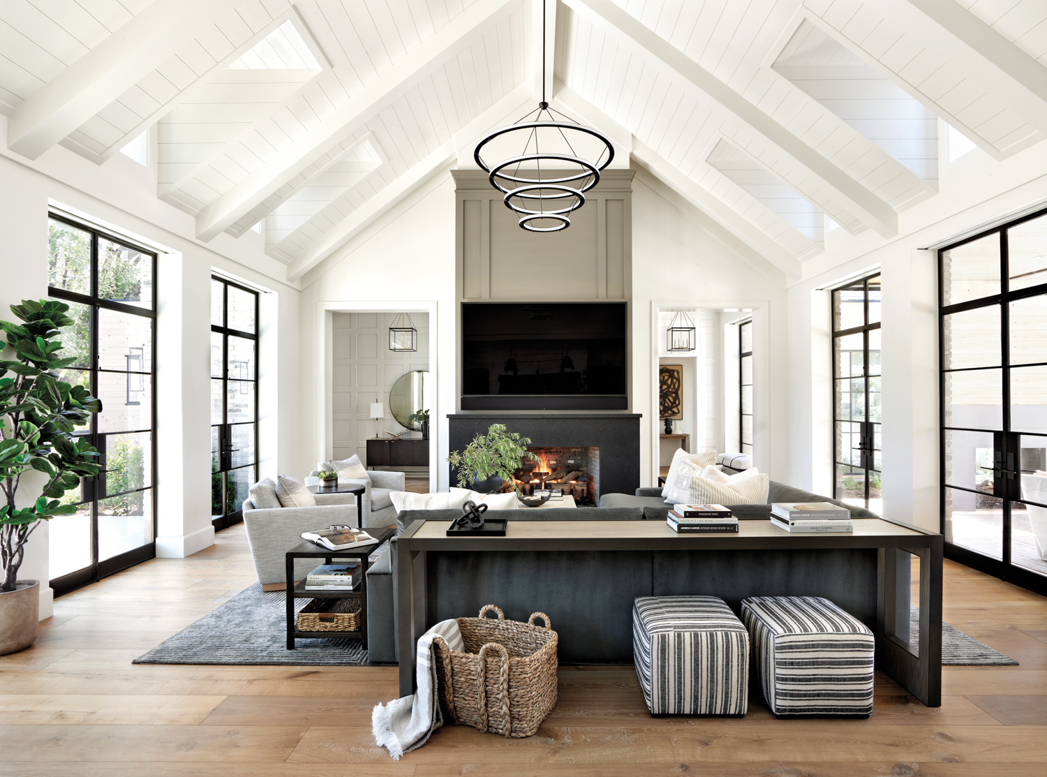 A great room in tones of white and gray with a vaulted ceilings. Steel-and-glass doors line either side of the room.
