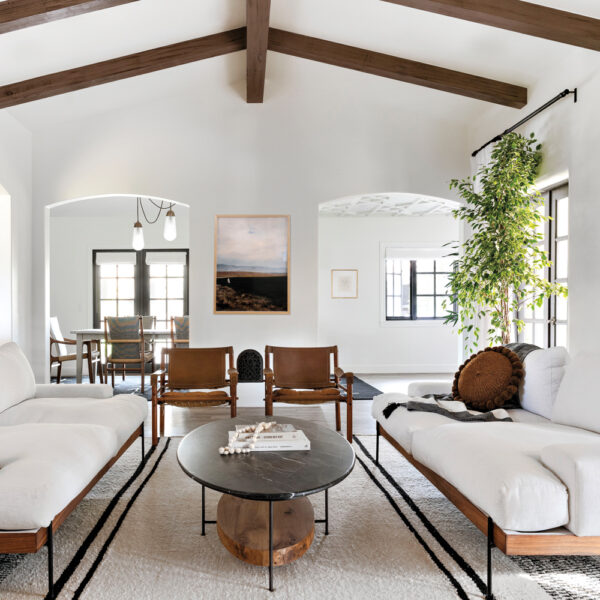 A white living room room with wood beams and a mix of white and wood furniture.