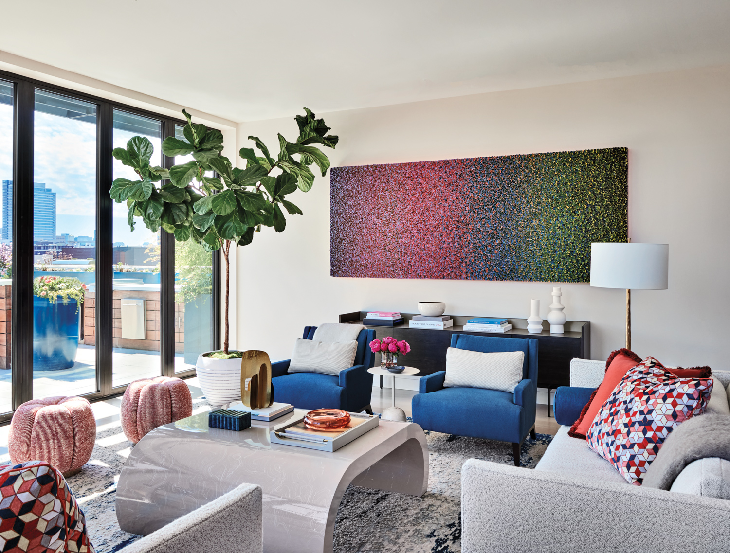Living room with large, colorful abstract painting and two blue armchairs.