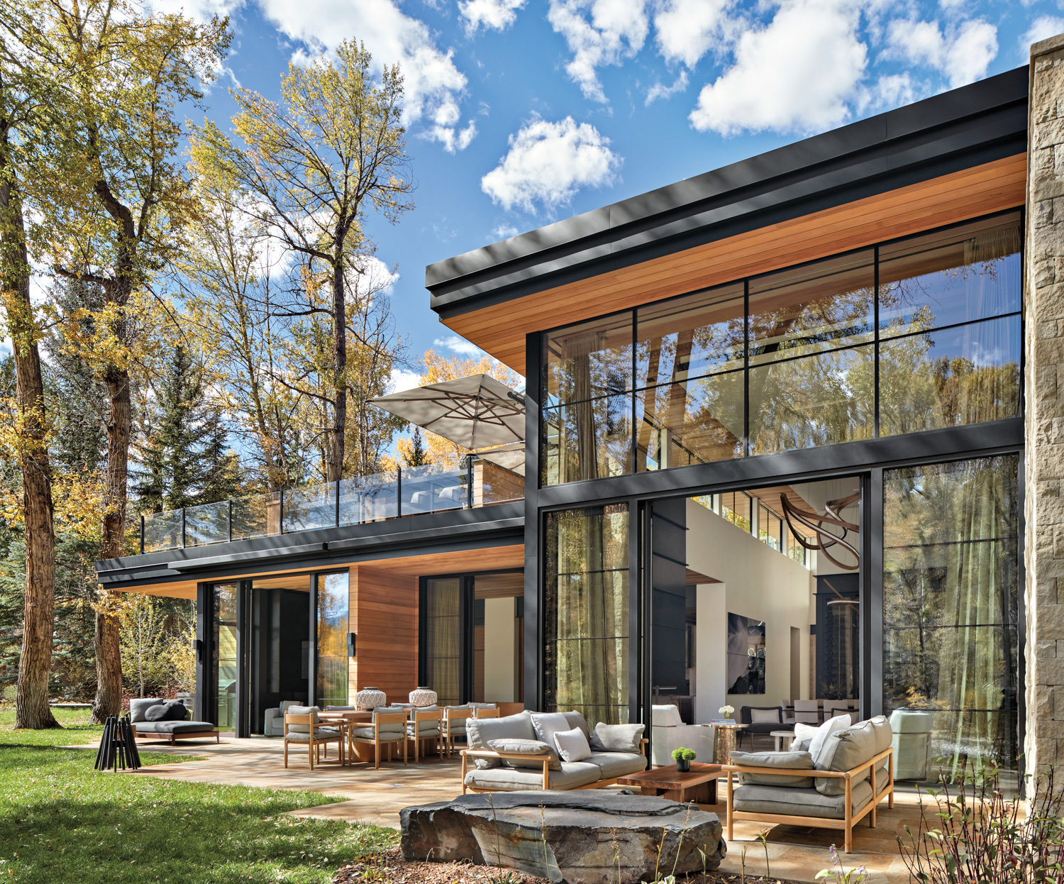 exterior of home with blackened-steel, cedar planks and limestone, with patio and dining area