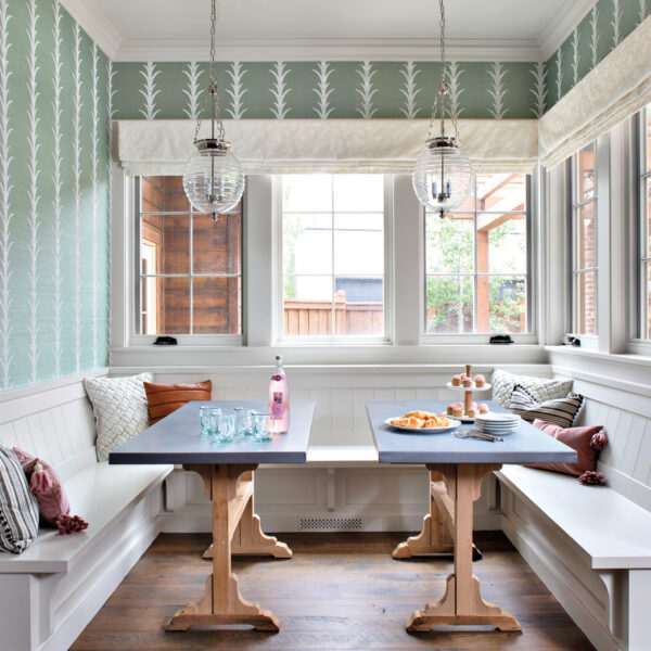 Plaid, Pattern And Patchwork Play Up A New Denver Home’s Old Soul breakfast nook with two custom tables and built-in banquette, with green printed wallpaper