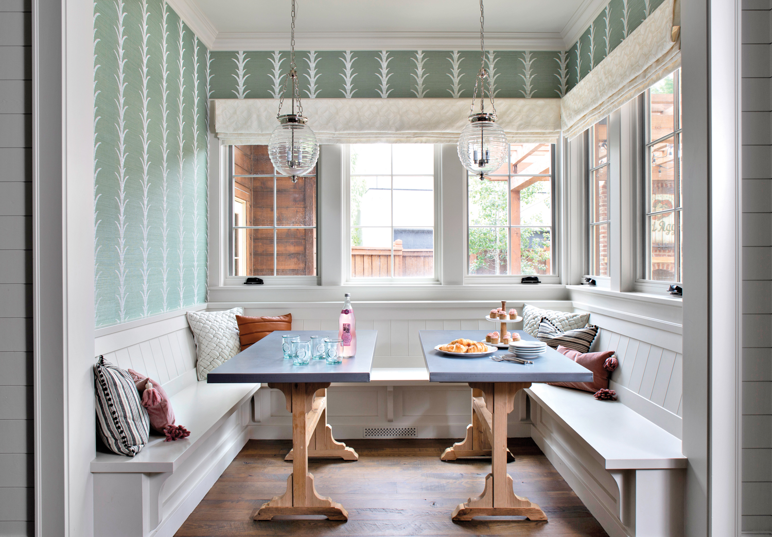 breakfast nook with two custom tables and built-in banquette, with green printed wallpaper