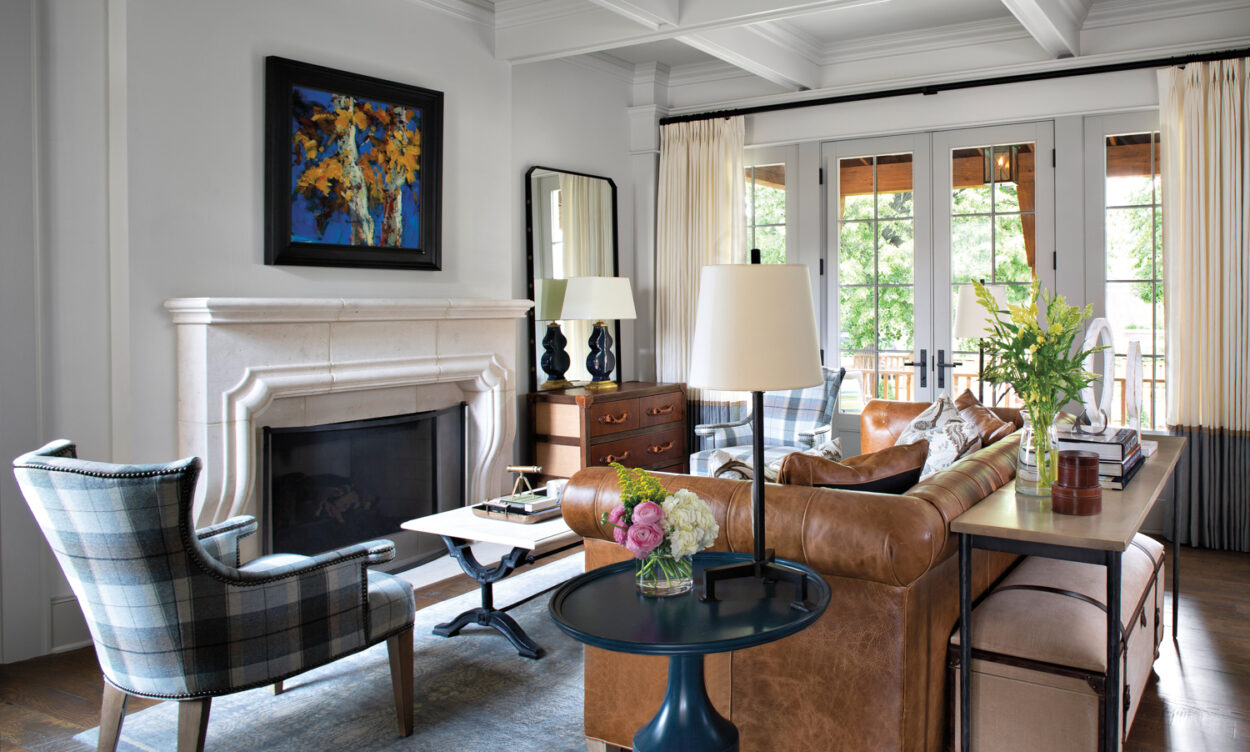 living room with camel leather sofa, plaid armchairs and cast stone mantle