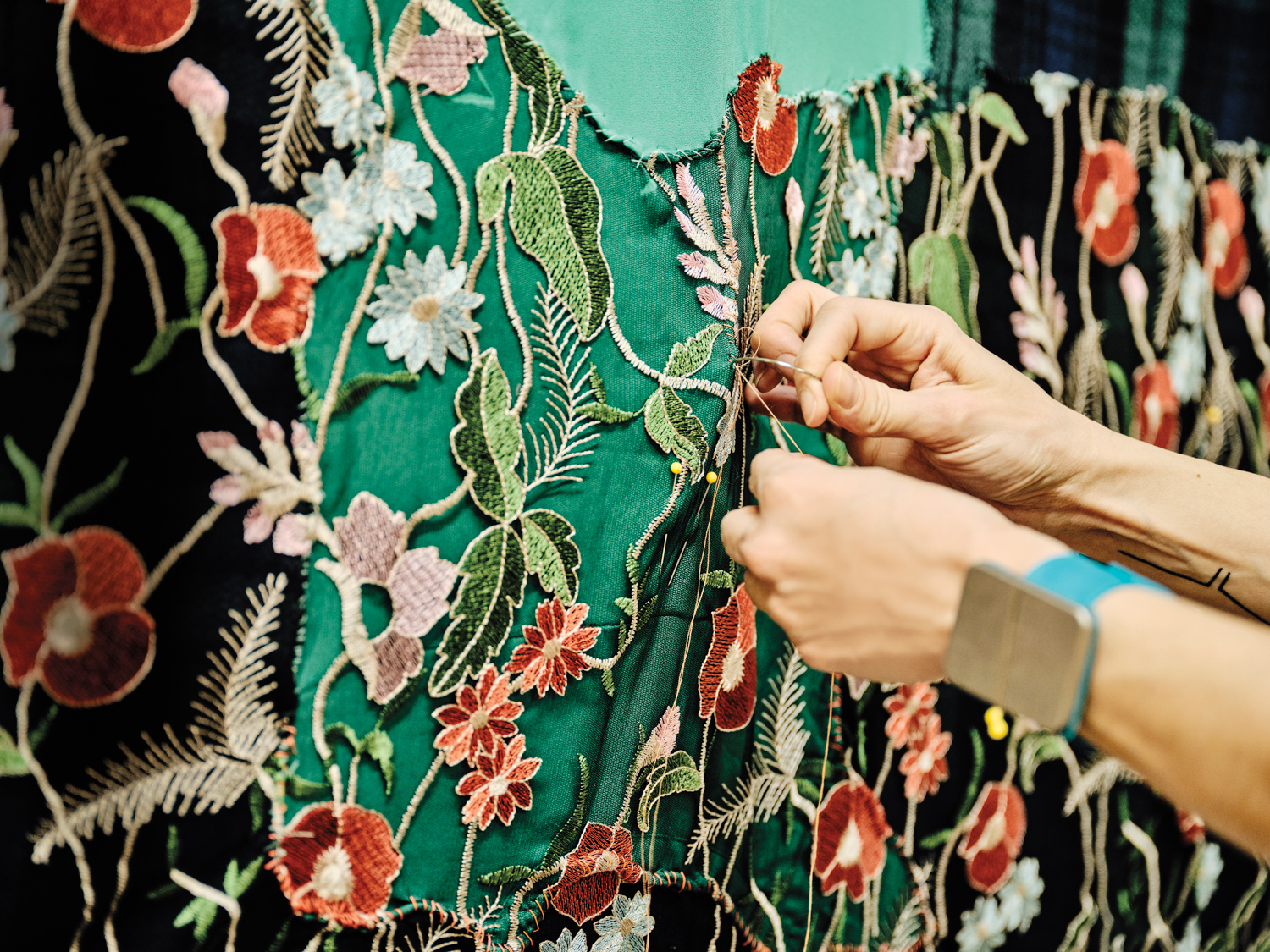 artist hands sewing on flower covered fabric remnant