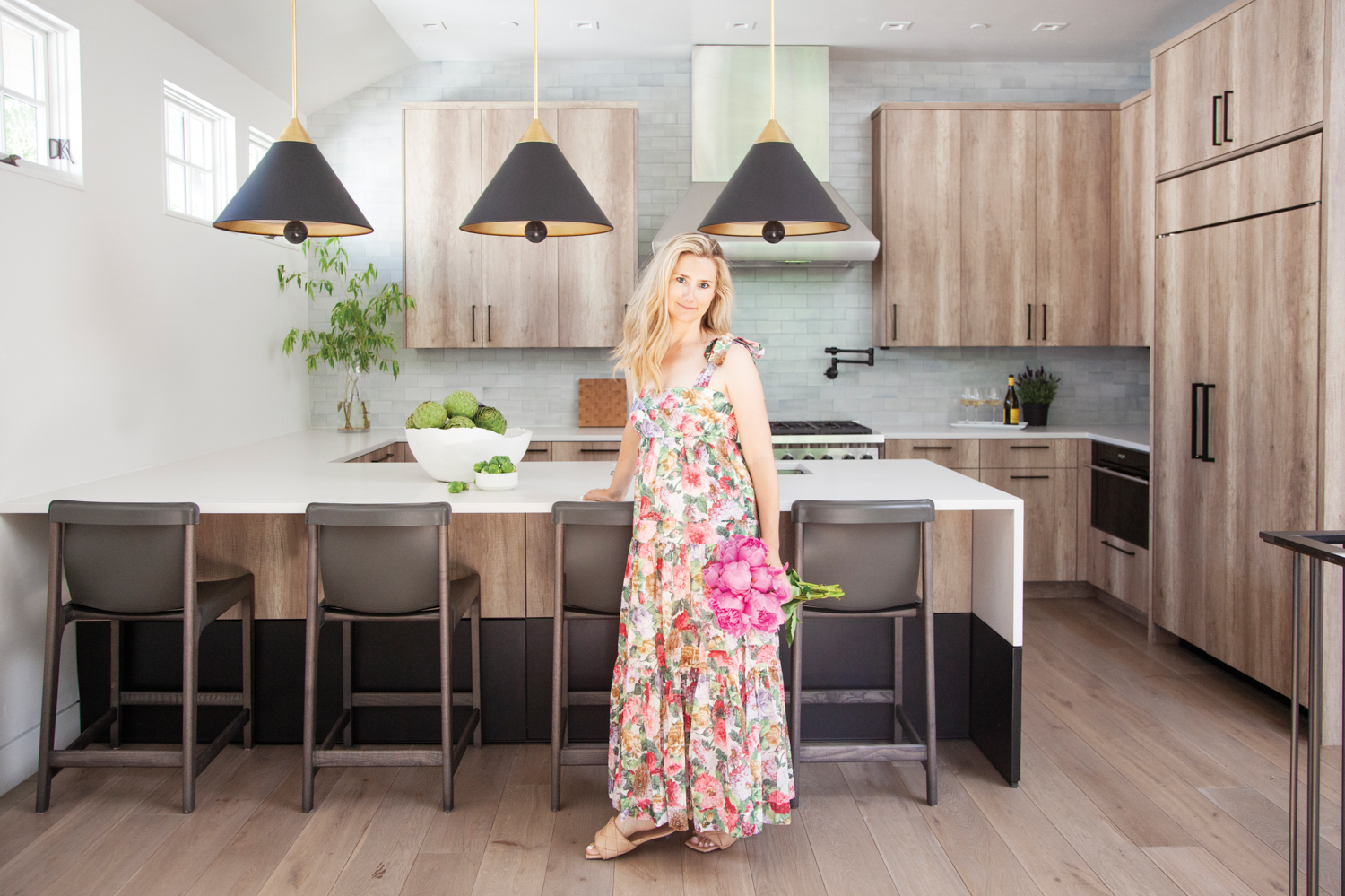 Kristin Dittmar standing by a kitchen island holding a bouquet of peonies