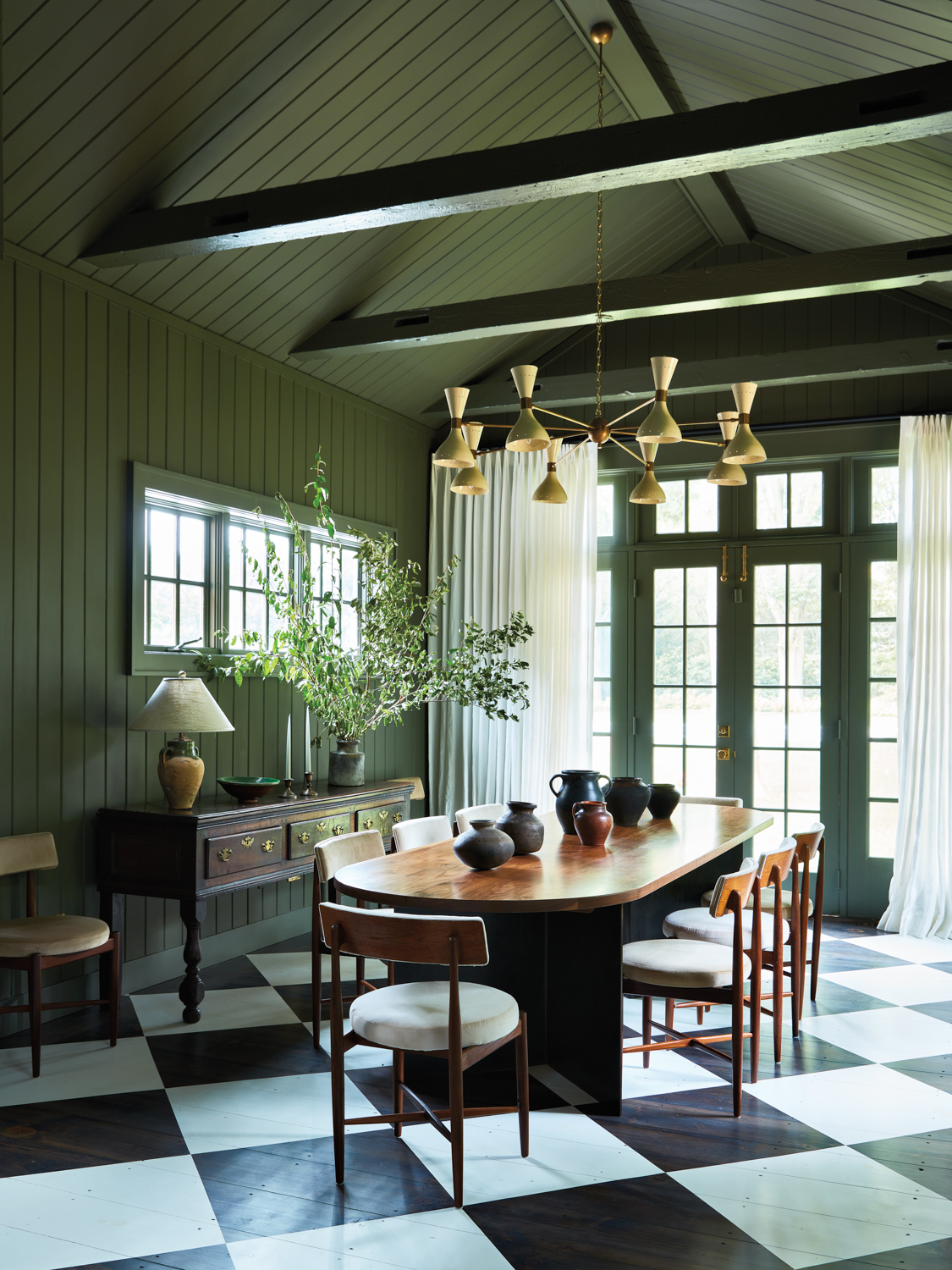 dining room with wooden oval table, teak chairs, and brass chandelier