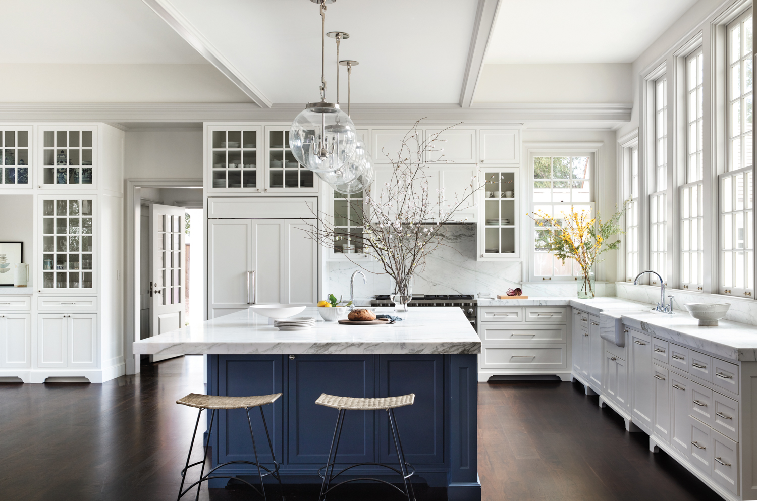 A blue kitchen island is in an otherwise white kitchen.