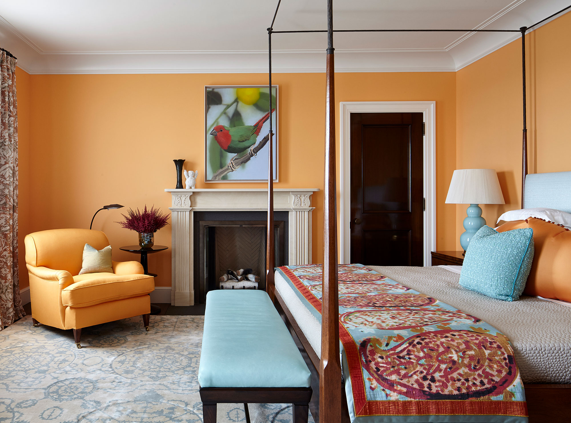 An orange bedroom with a fireplace and a four poster bed.