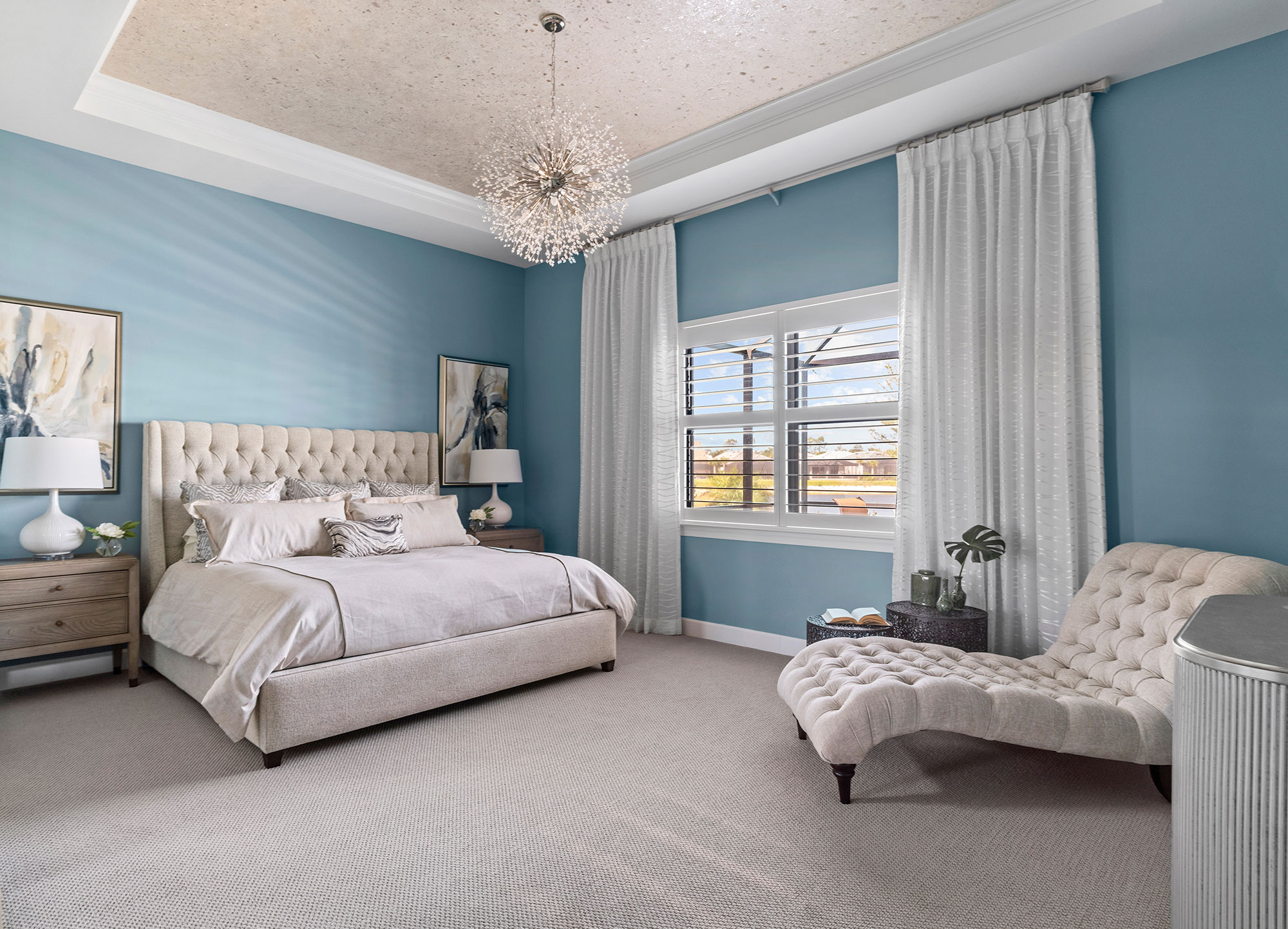 A blue bedroom with a taupe upholstered bed and a matching chaise