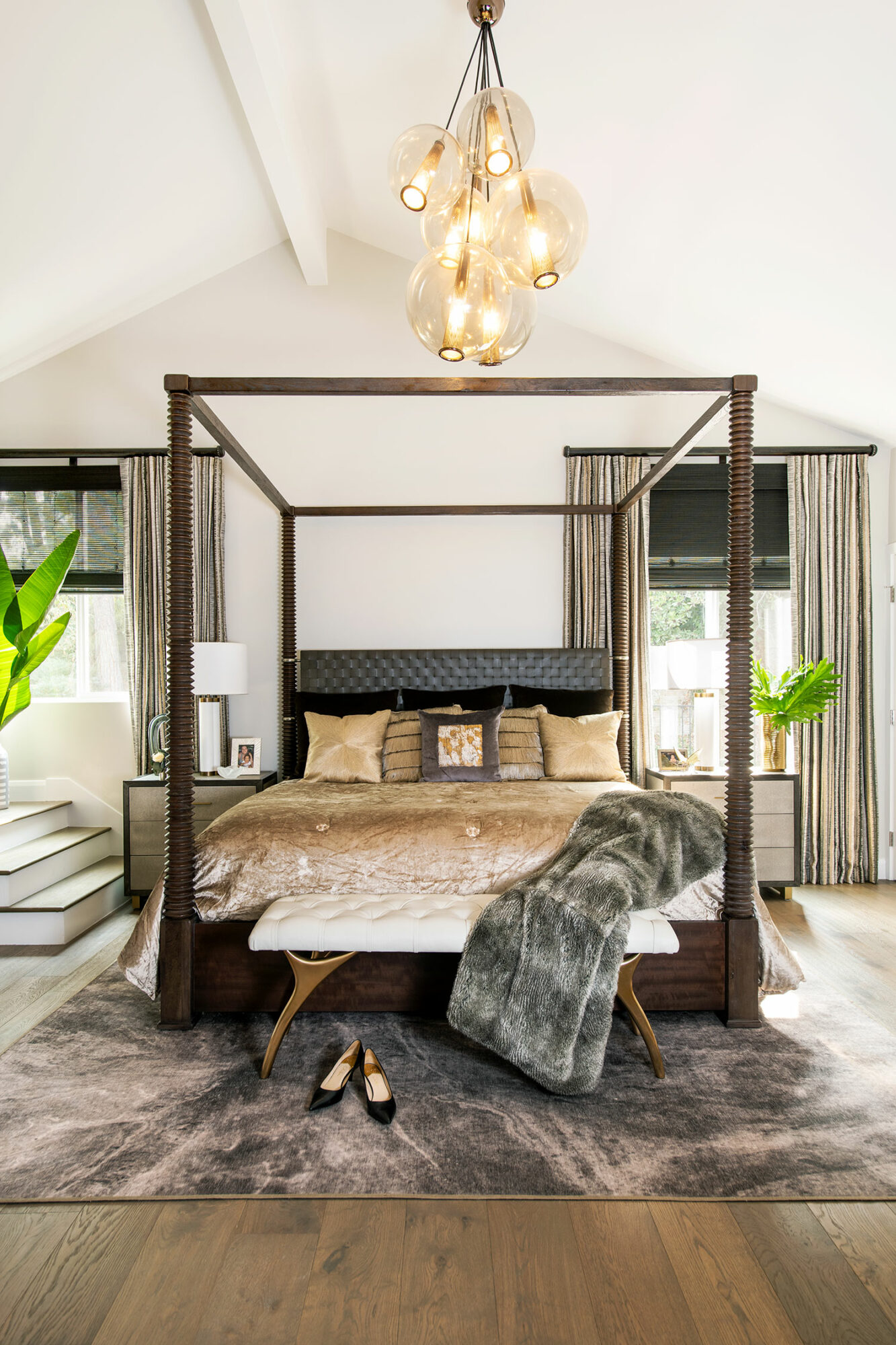 A light gray bedroom with a brown four-poster bed and a modern chandelier.