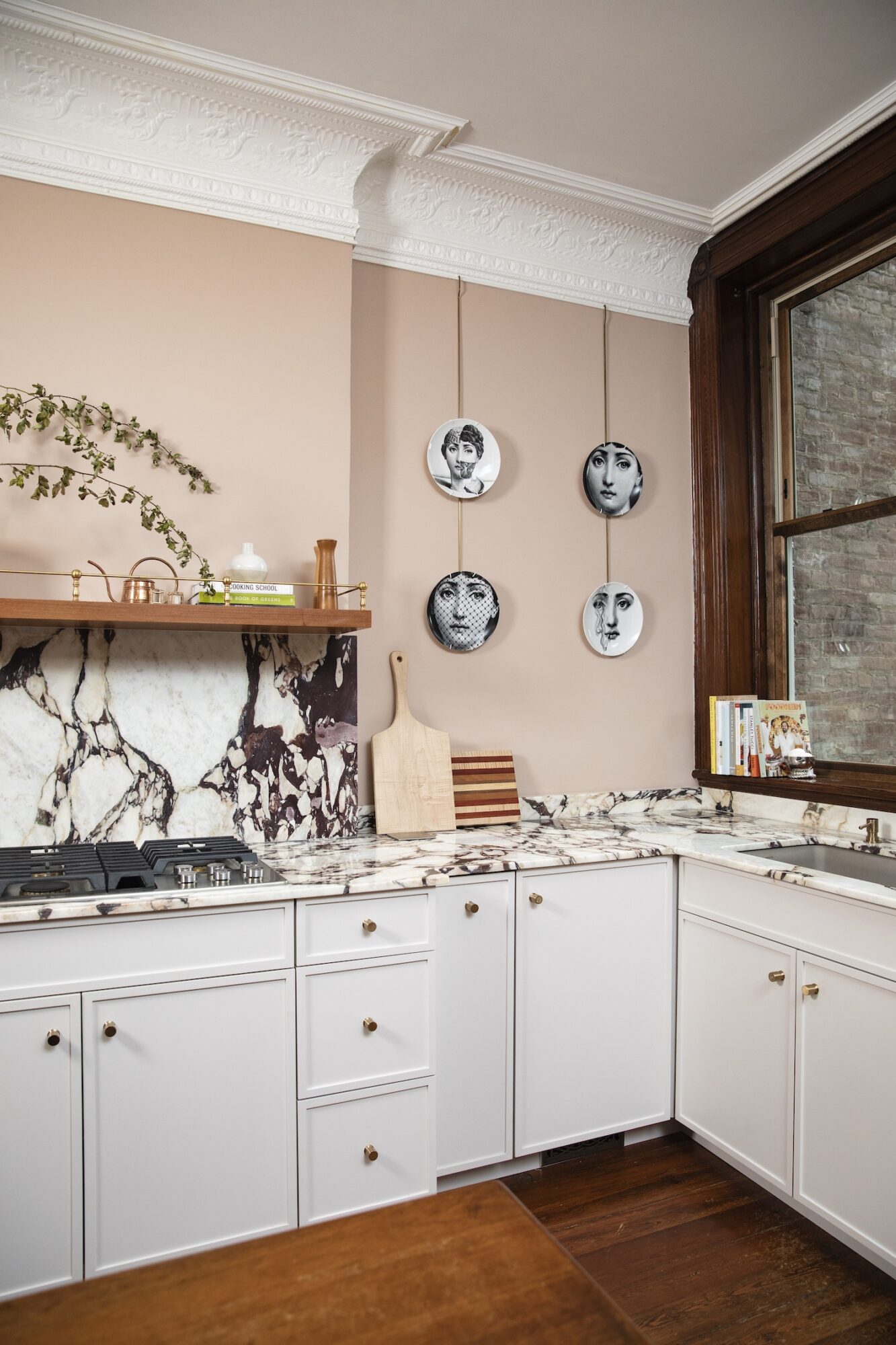 A kitchen with peachy-pink walls, white cabinetry, and black-and-white stone countertops and backsplash.