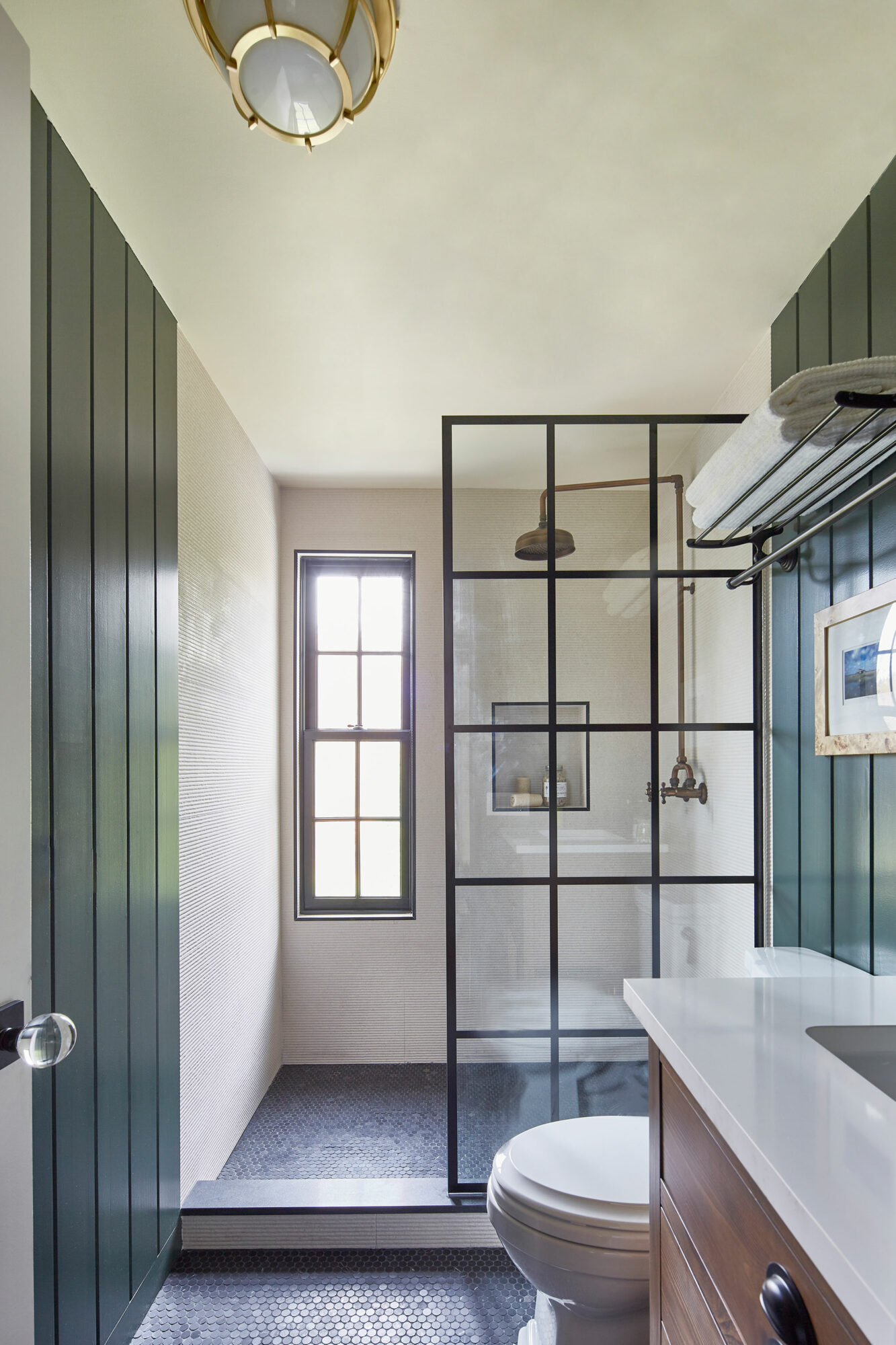 dark green was the best paint color for the paneling in this small bathroom with a black steel shower door