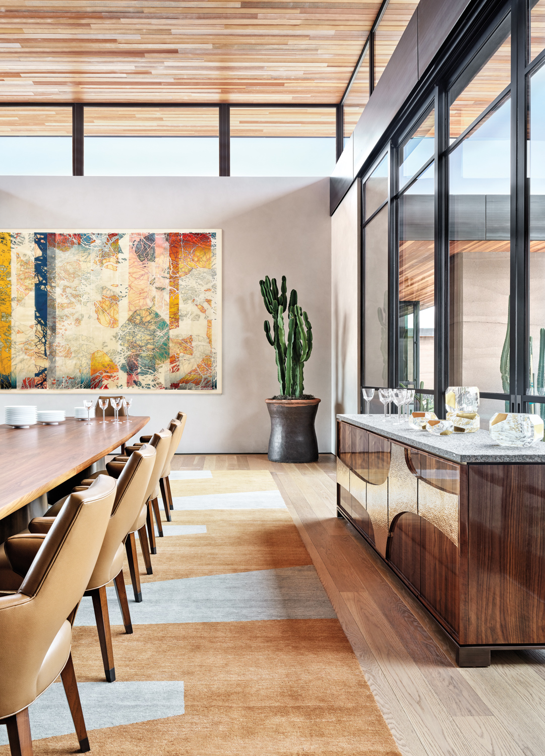 dining room with live-edge dining table, large abstract painting and a walnut-and-granite-and-hammered brass cabinet.