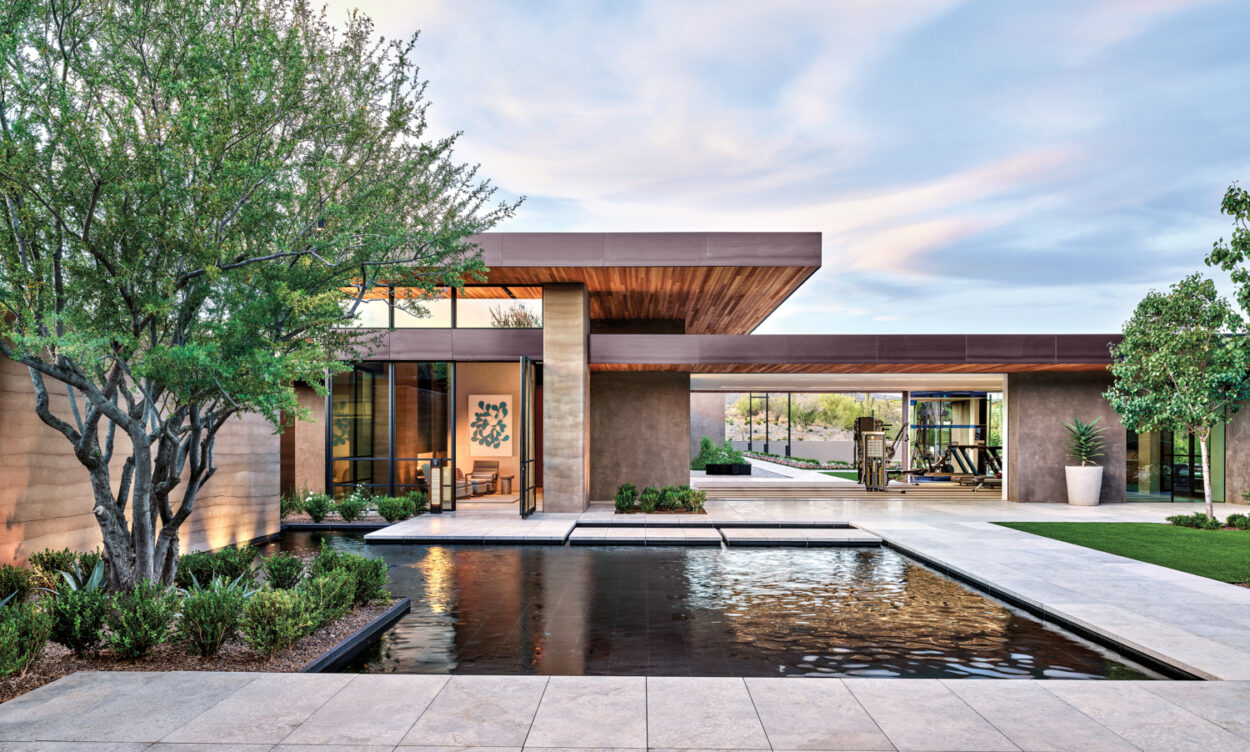A courtyard in the center of a modern compound with a rectangular pool-like water feature