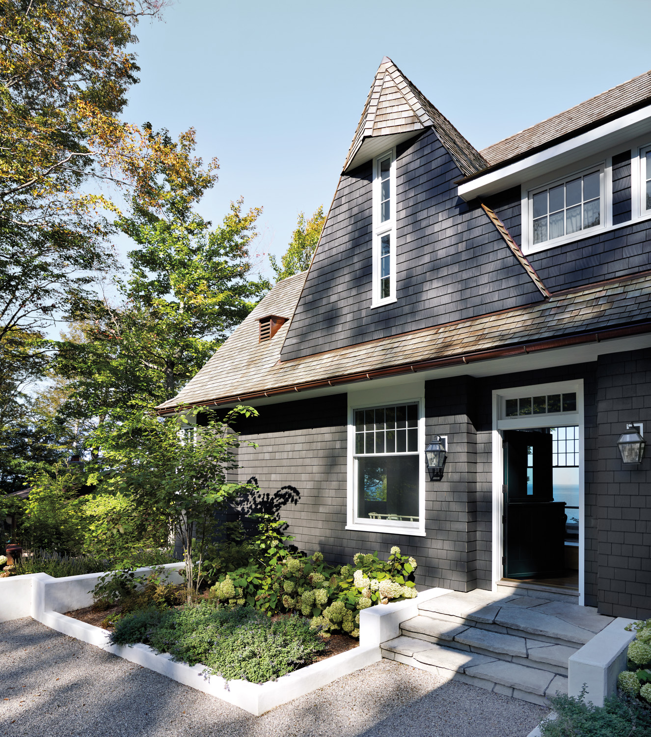 front of a dark shingle-style house