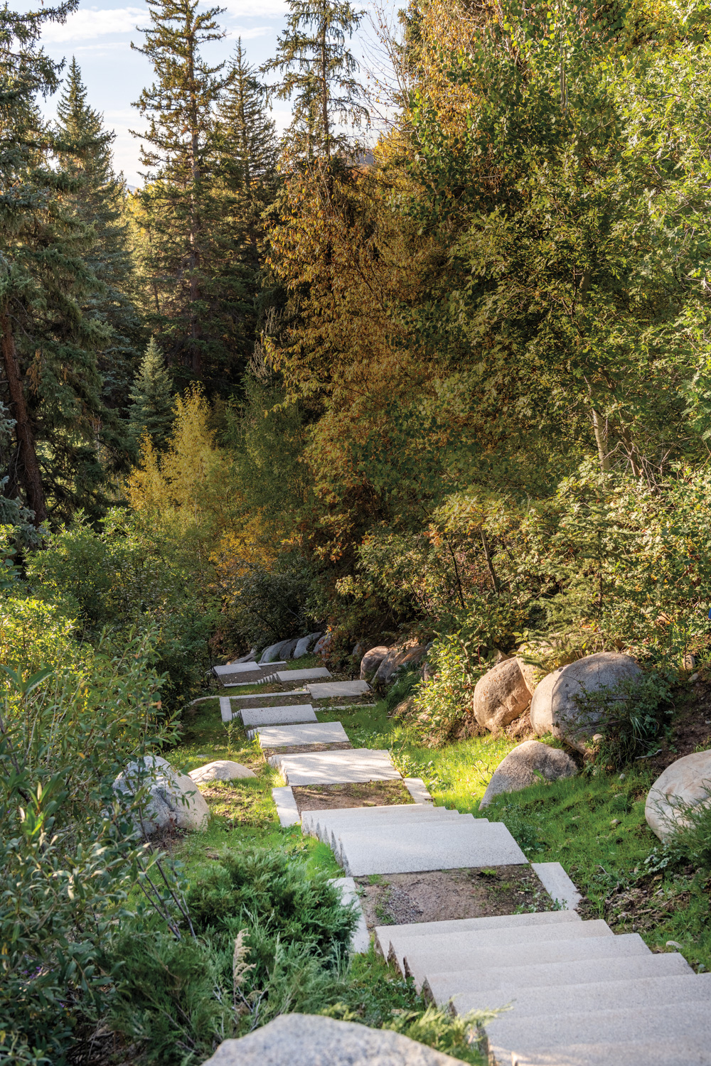 Limestone steps going down a creek surrounded by boulders and greenery