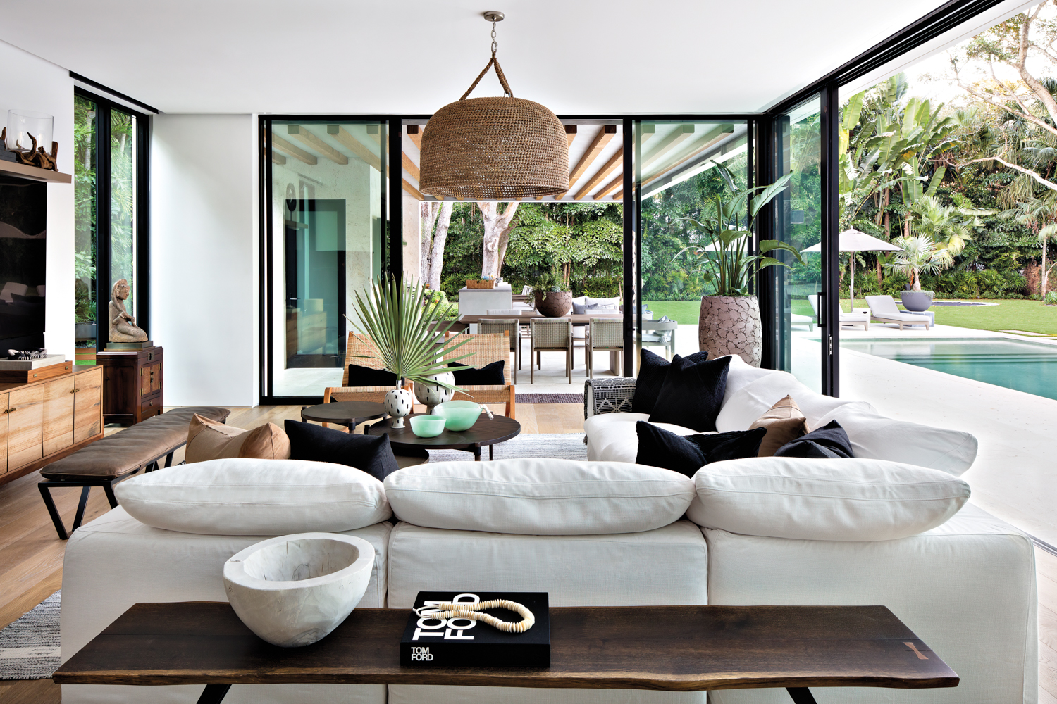 family room with oversize white sectional, rope overhead pendant and glass doors that open to lush backyard