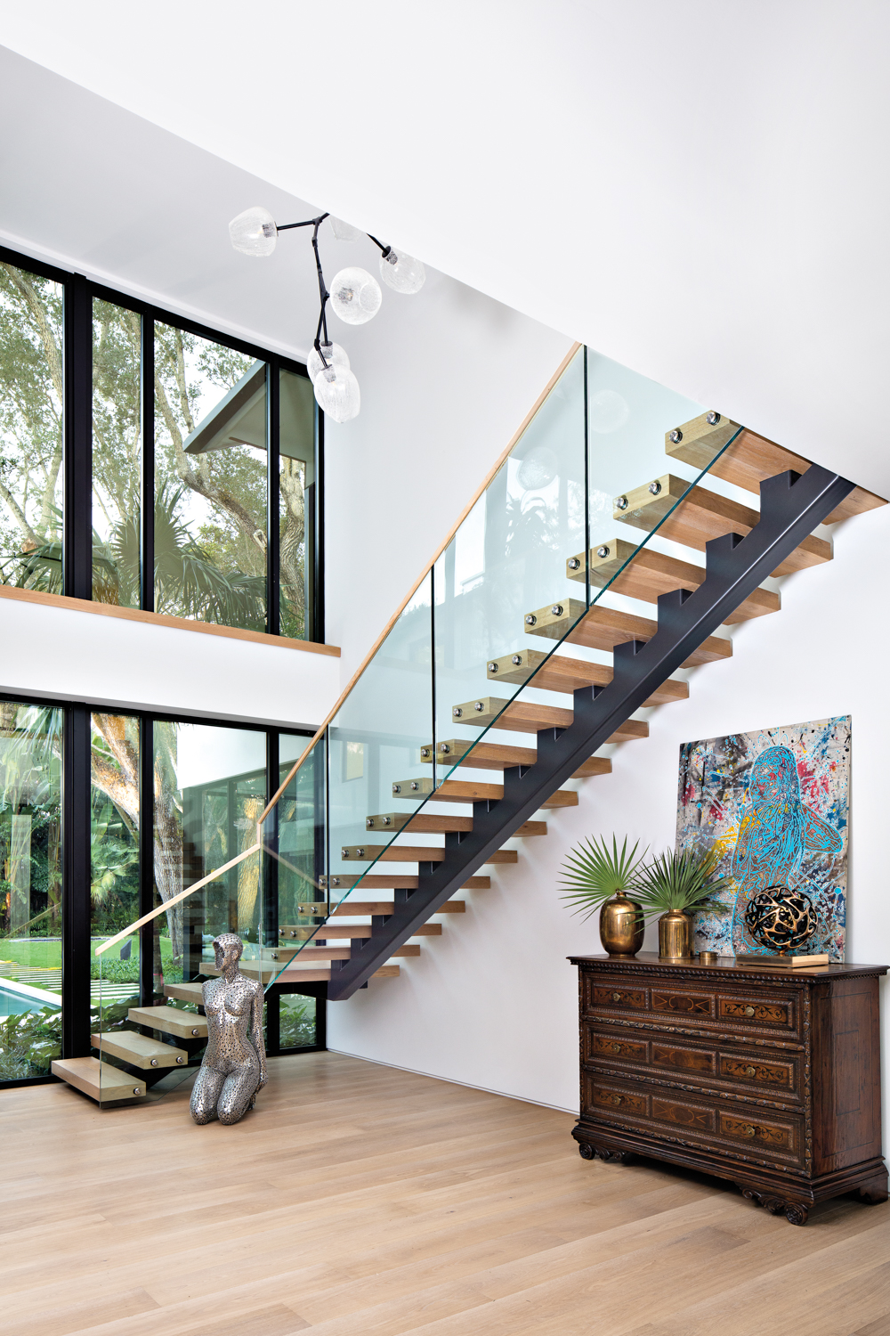 white-walled foyer with glass-and-wood staircase,...