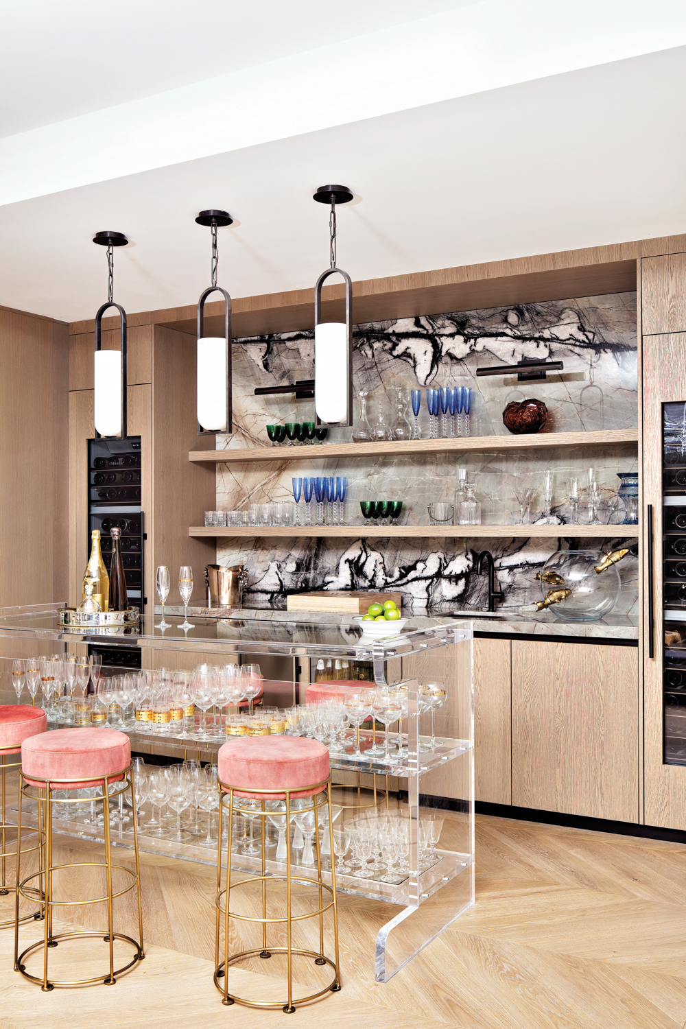 bar area with lucite bar, pink-topped stools, wood cabinetry and quartzite backsplash