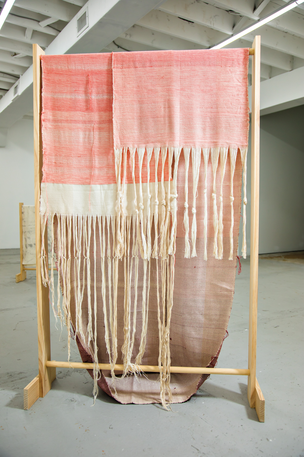 pink woven cloth hanging from handmade maple frame