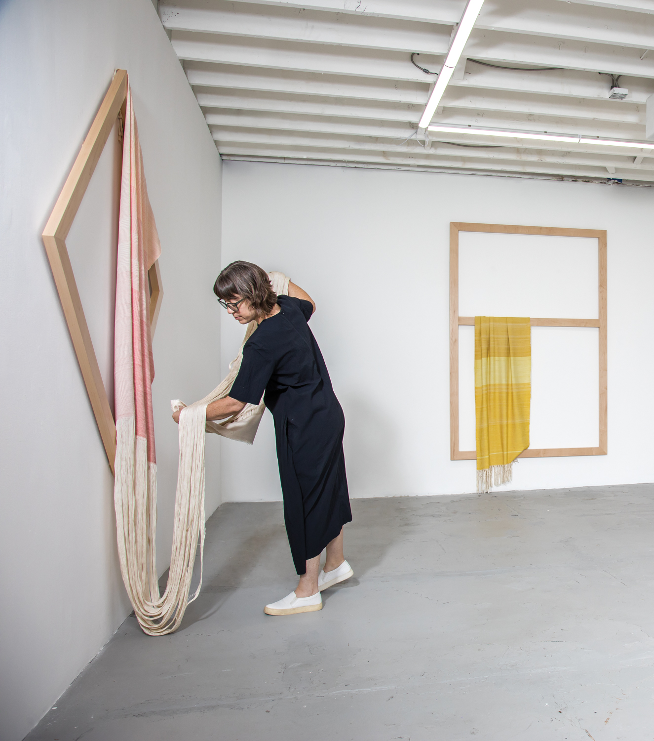 artist Frances Trombly draping a pink cloth on a maple frame in her studio
