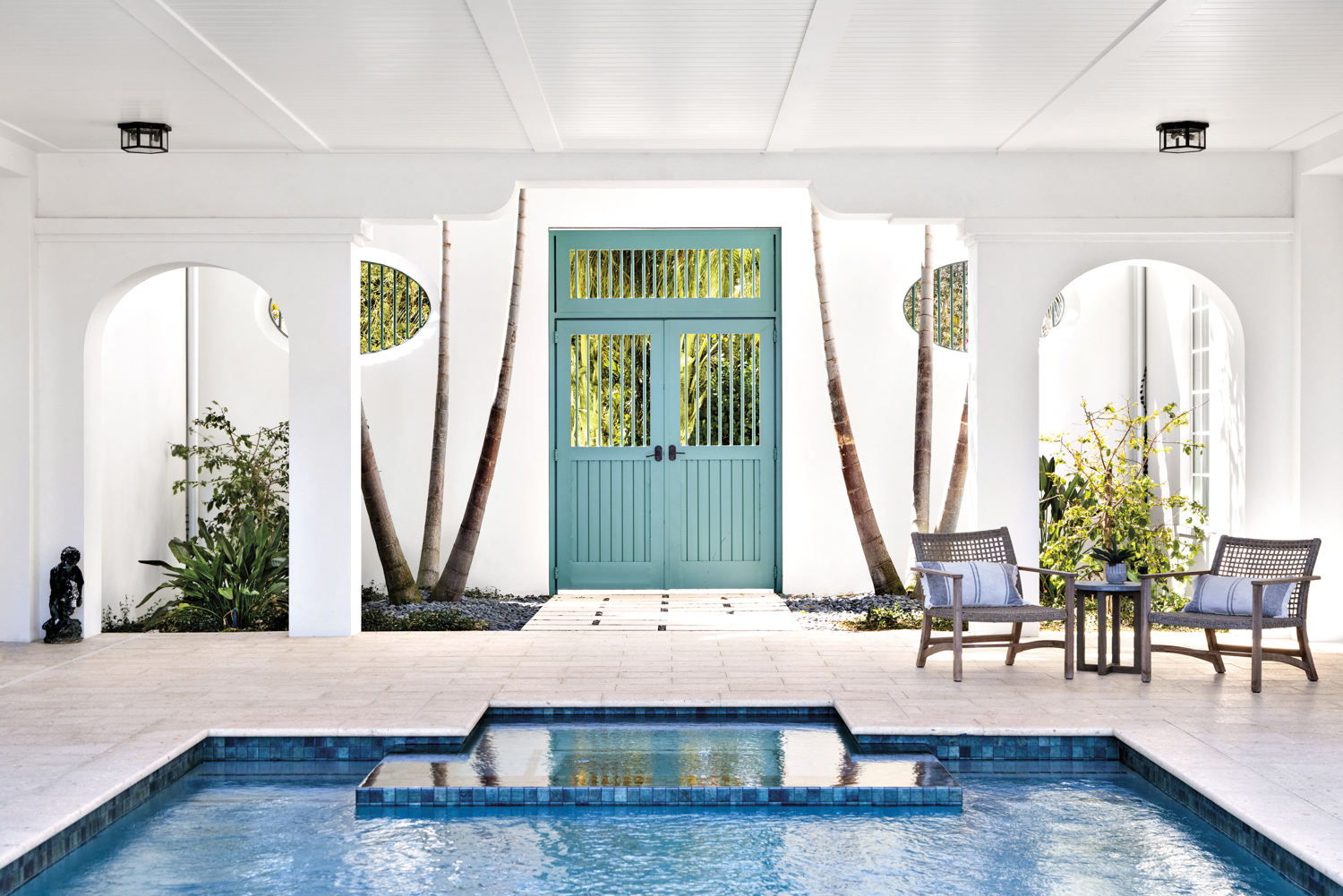 logga with white walls and ceiling, coastal green-colored door, pool and sitting area
