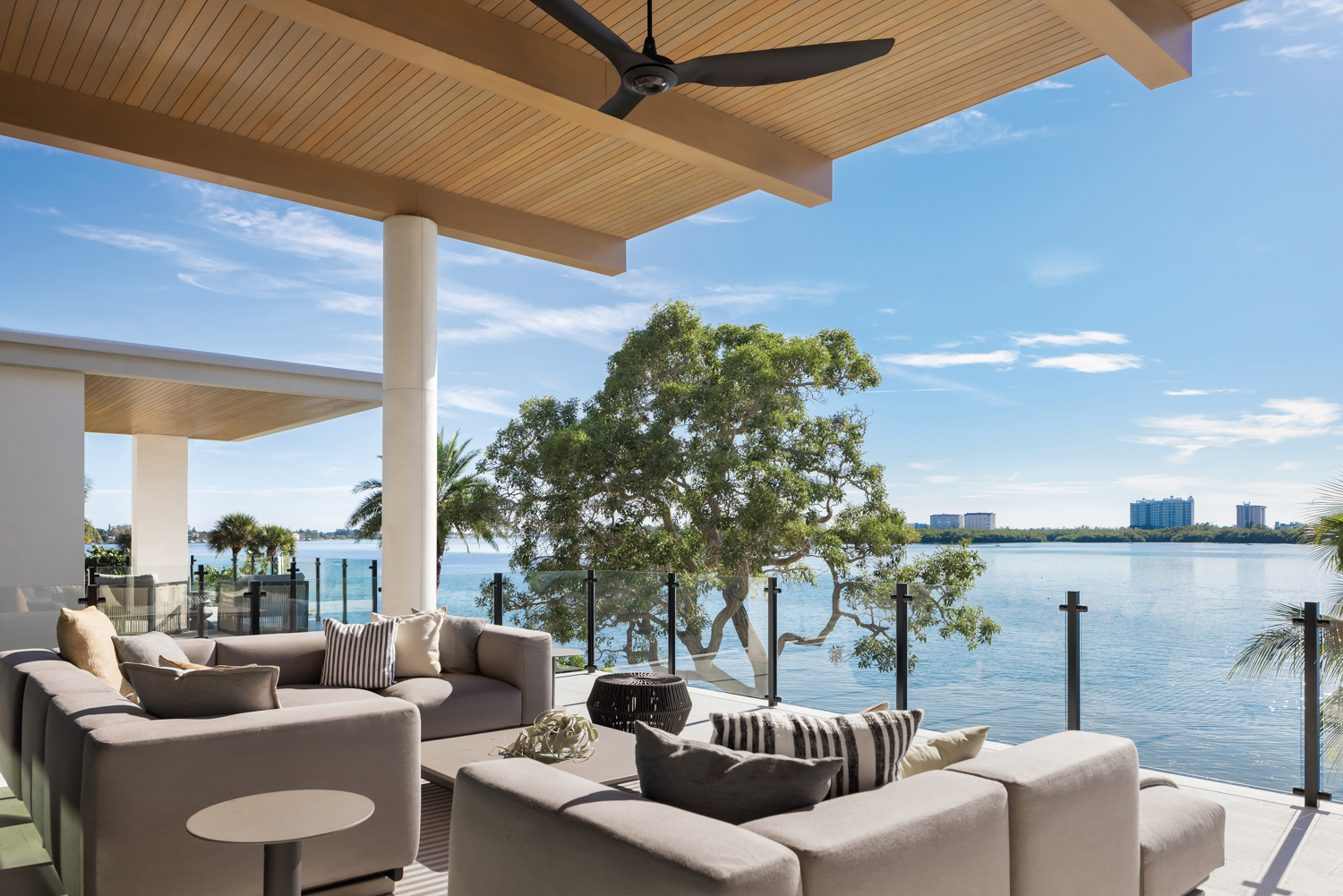 outdoor living area terrace with gray sectionals, coffee table and side tables overlooking waterway