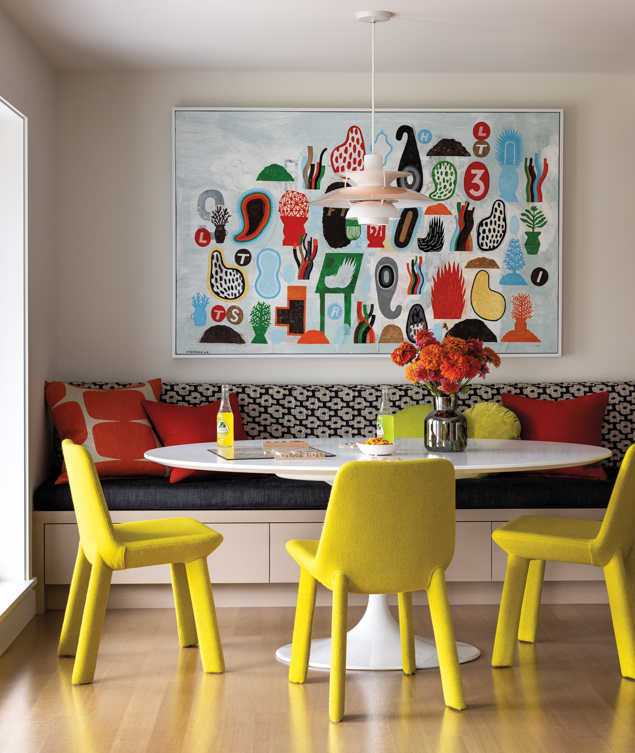 midcentury-modern breakfast nook with yellow chairs and banquette with colorful art