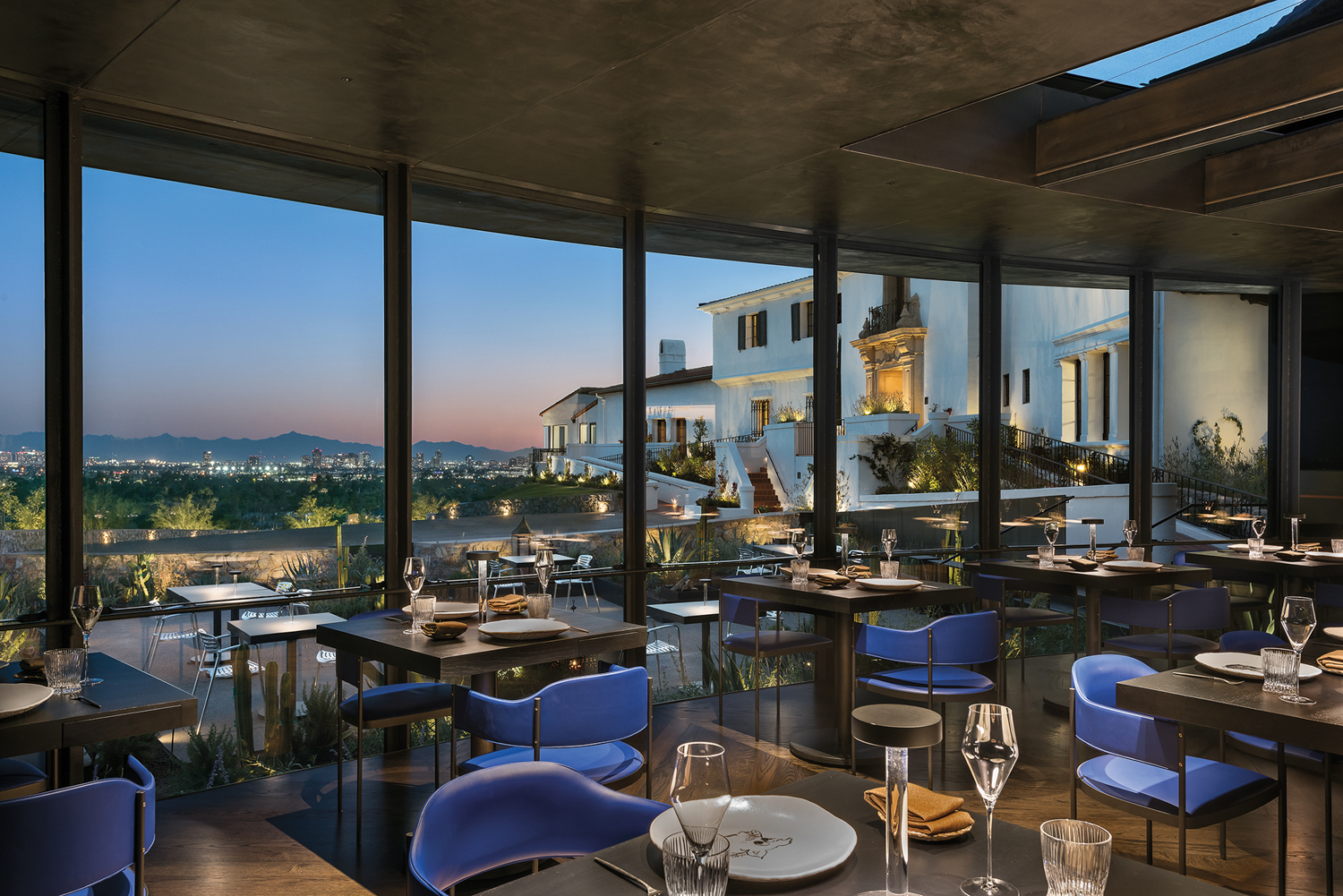 Restaurant with blue chairs overlooking city views.